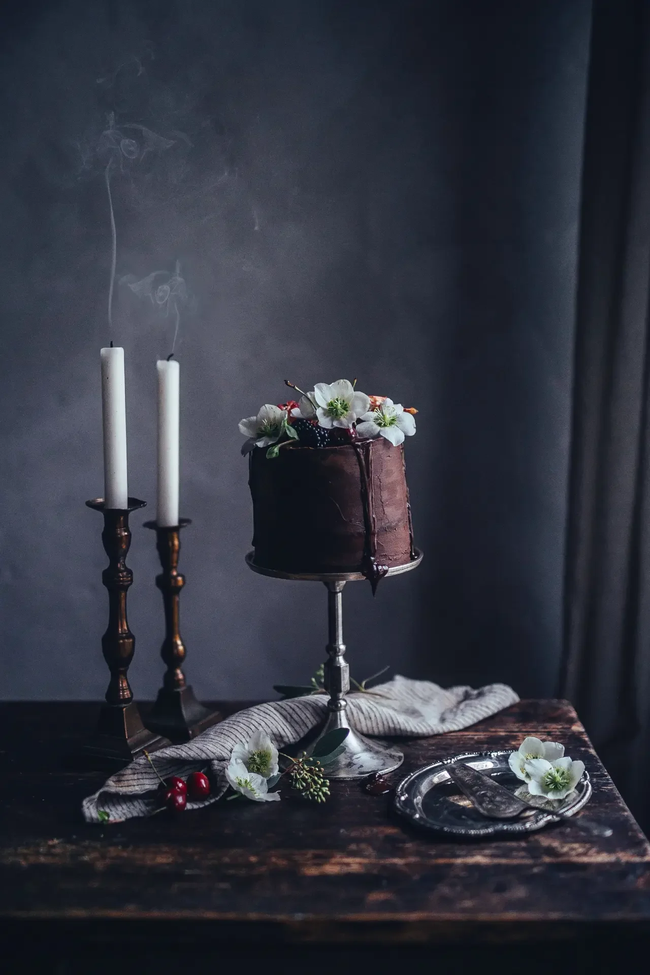 Dark chocolate cake presented on cake stand with elegant candlelit styling