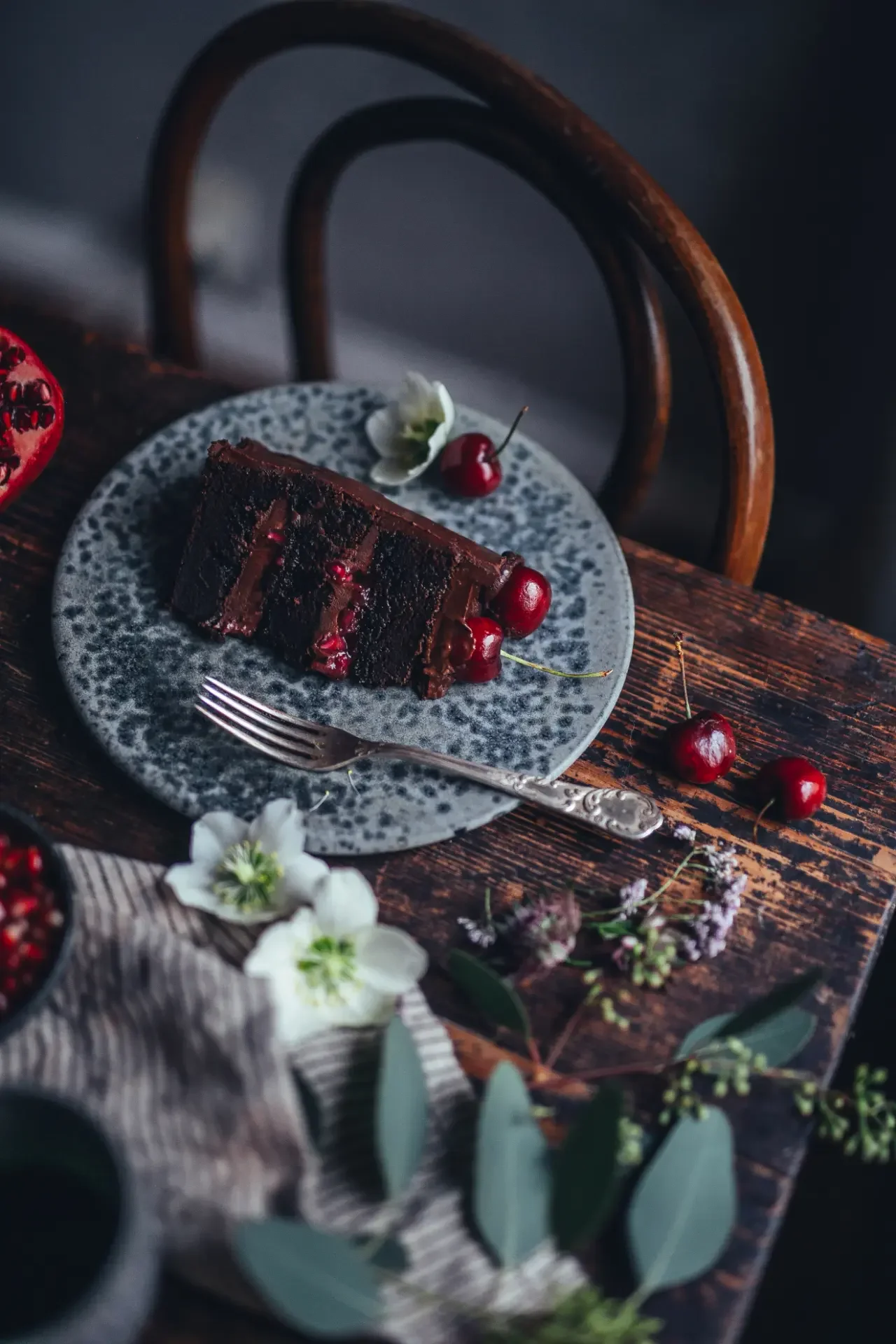 Chocolate cake slice served with fresh cherries and pomegranate seeds