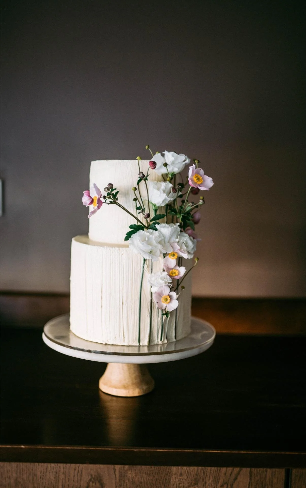 Modern two-tier wedding cake with cascading fresh white and blue flowers