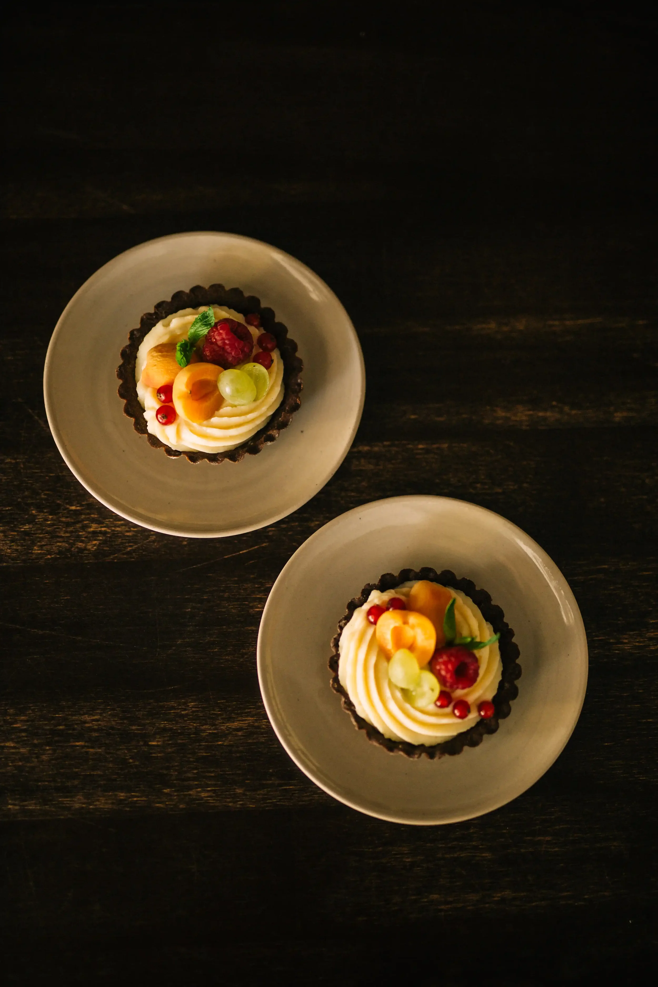 Two handmade cheesecake tartes decorated with fresh seasonal fruits
