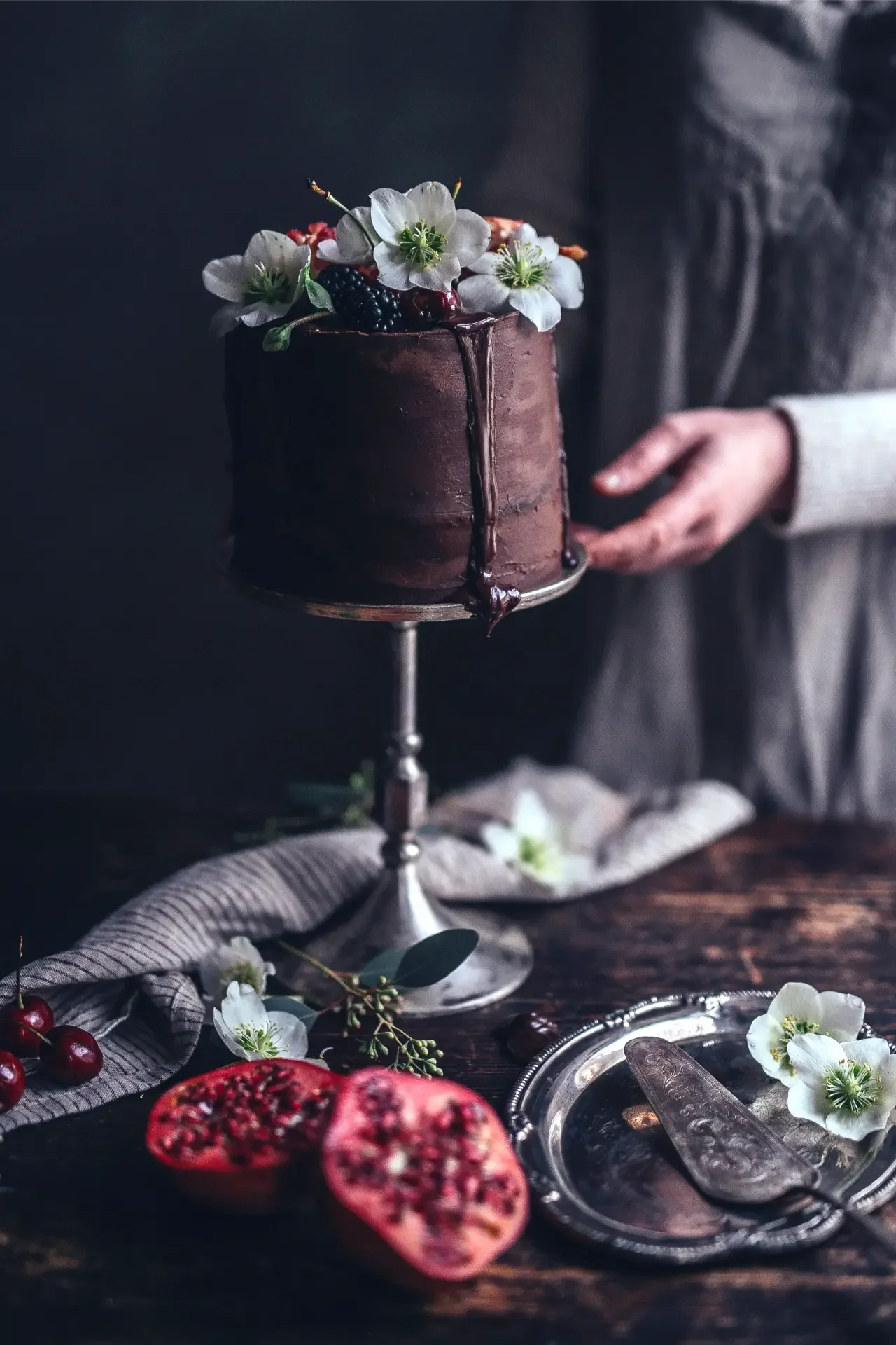 Hand serving chocolate pomegranate cake on artisan dessert table