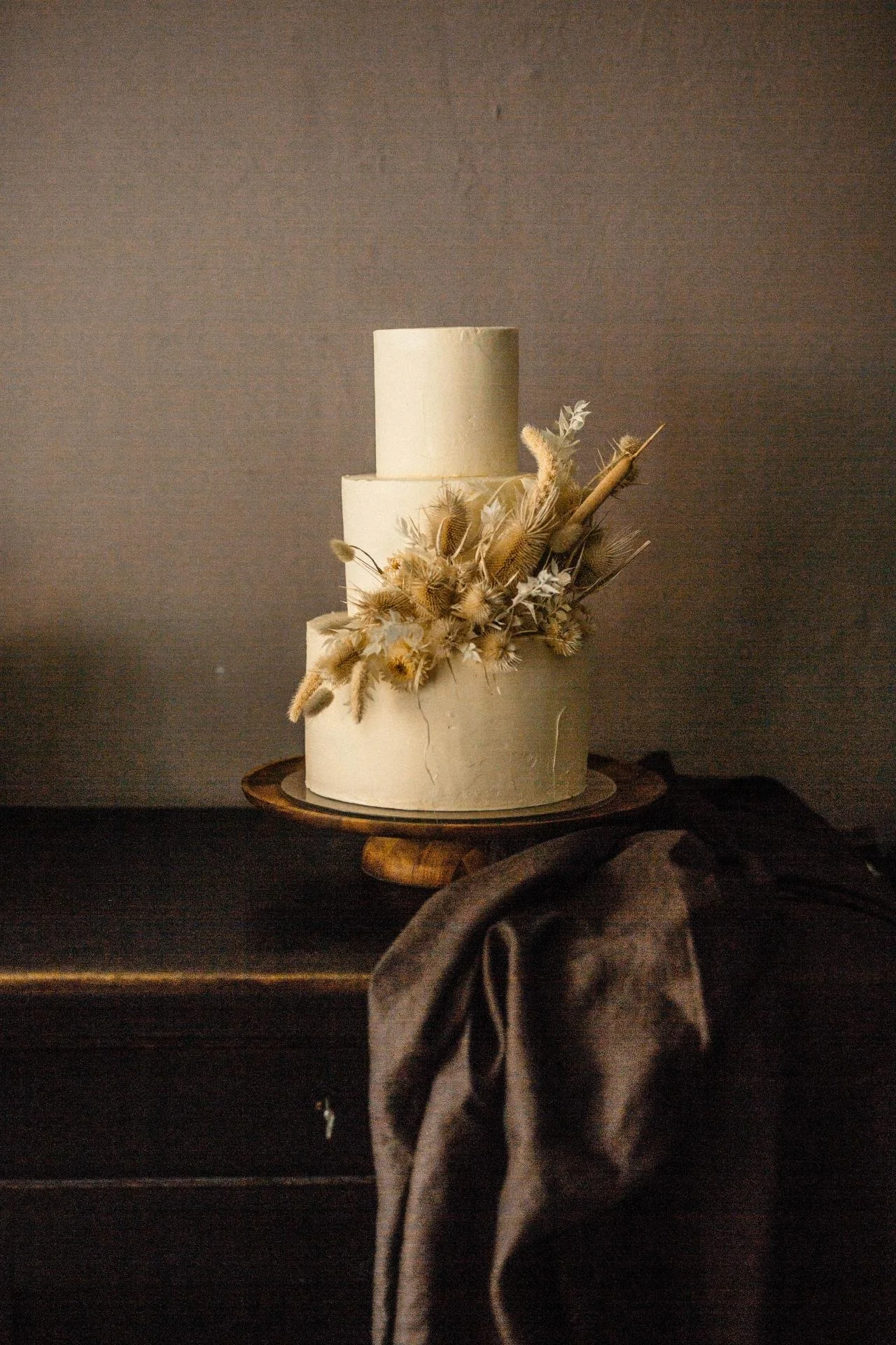 Minimal two-tier wedding cake with dried floral decoration in warm neutral tones