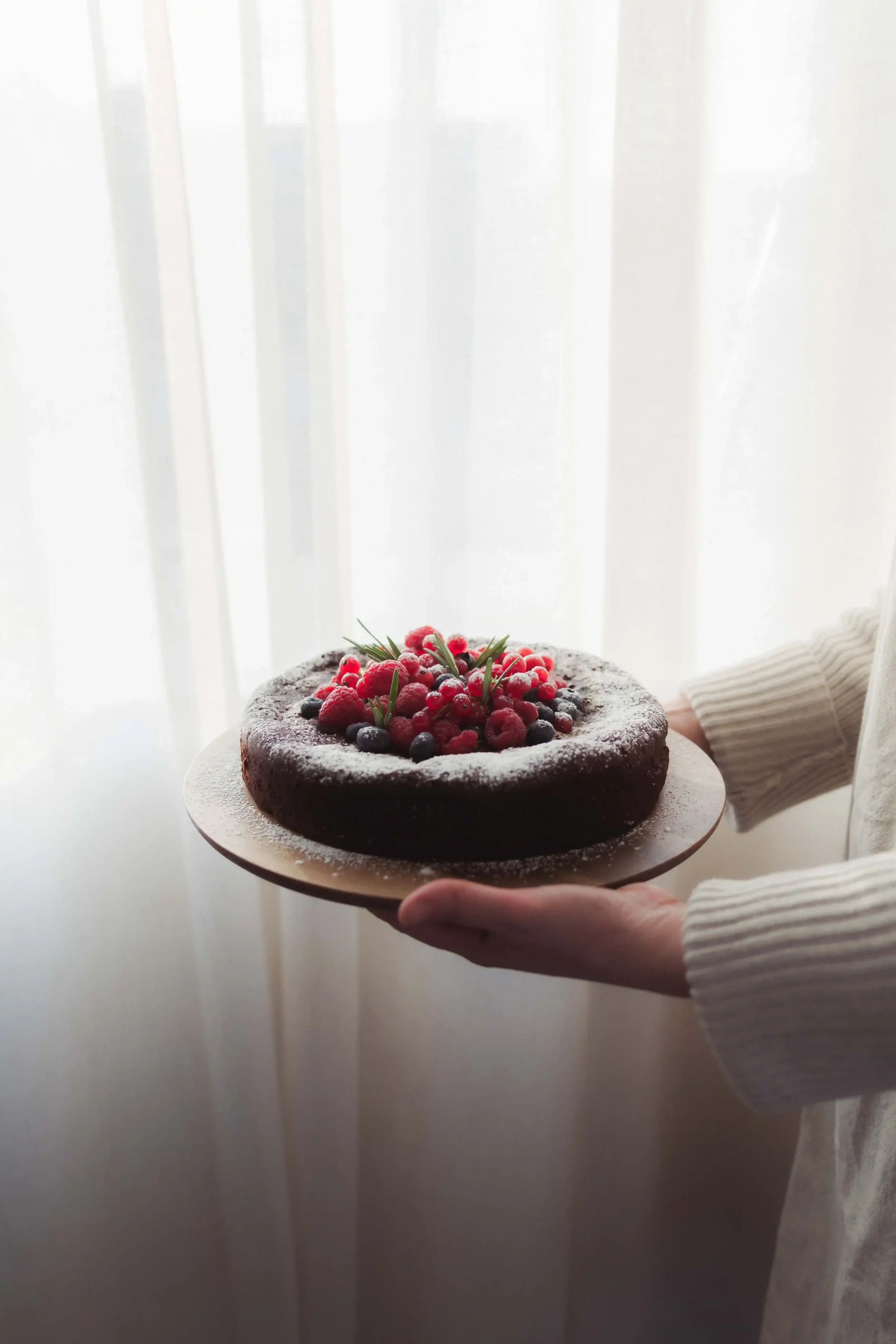 Hand holding seasonal berry cake prepared for catering and celebrations
