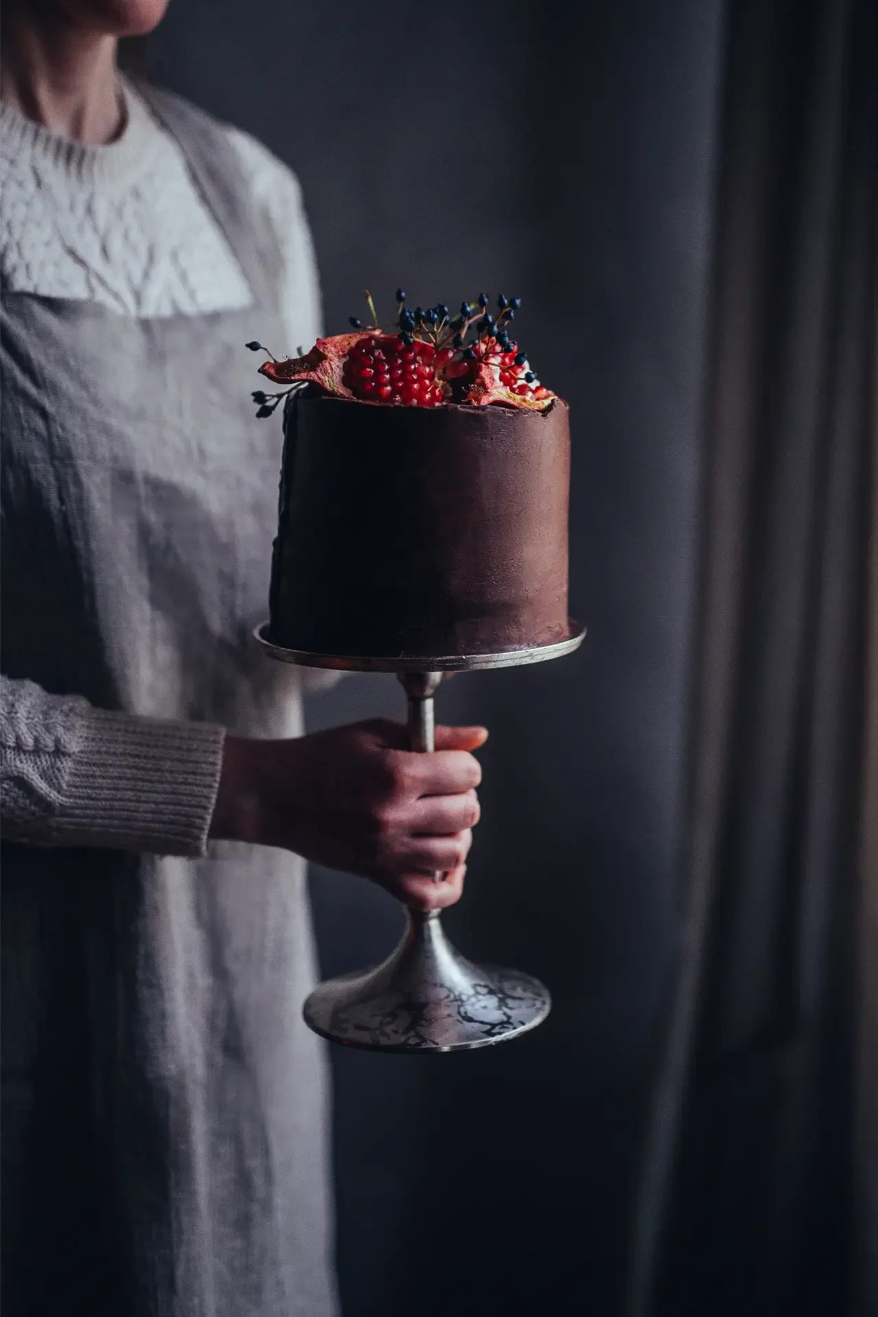 Chocolate cake topped with fresh pomegranate seeds and seasonal flowers