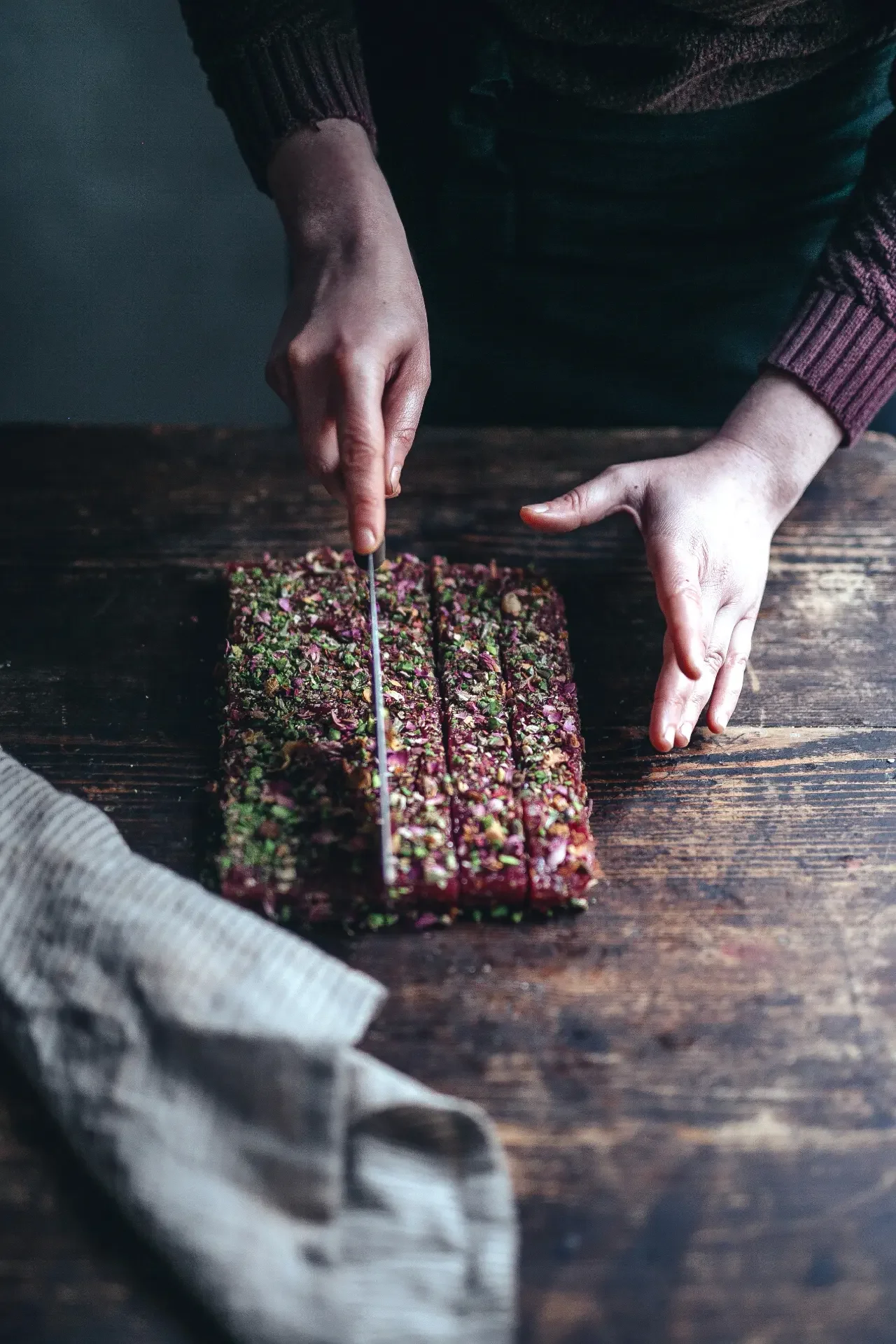 Cutting handmade lokum with pistachios and fragrant rose buds