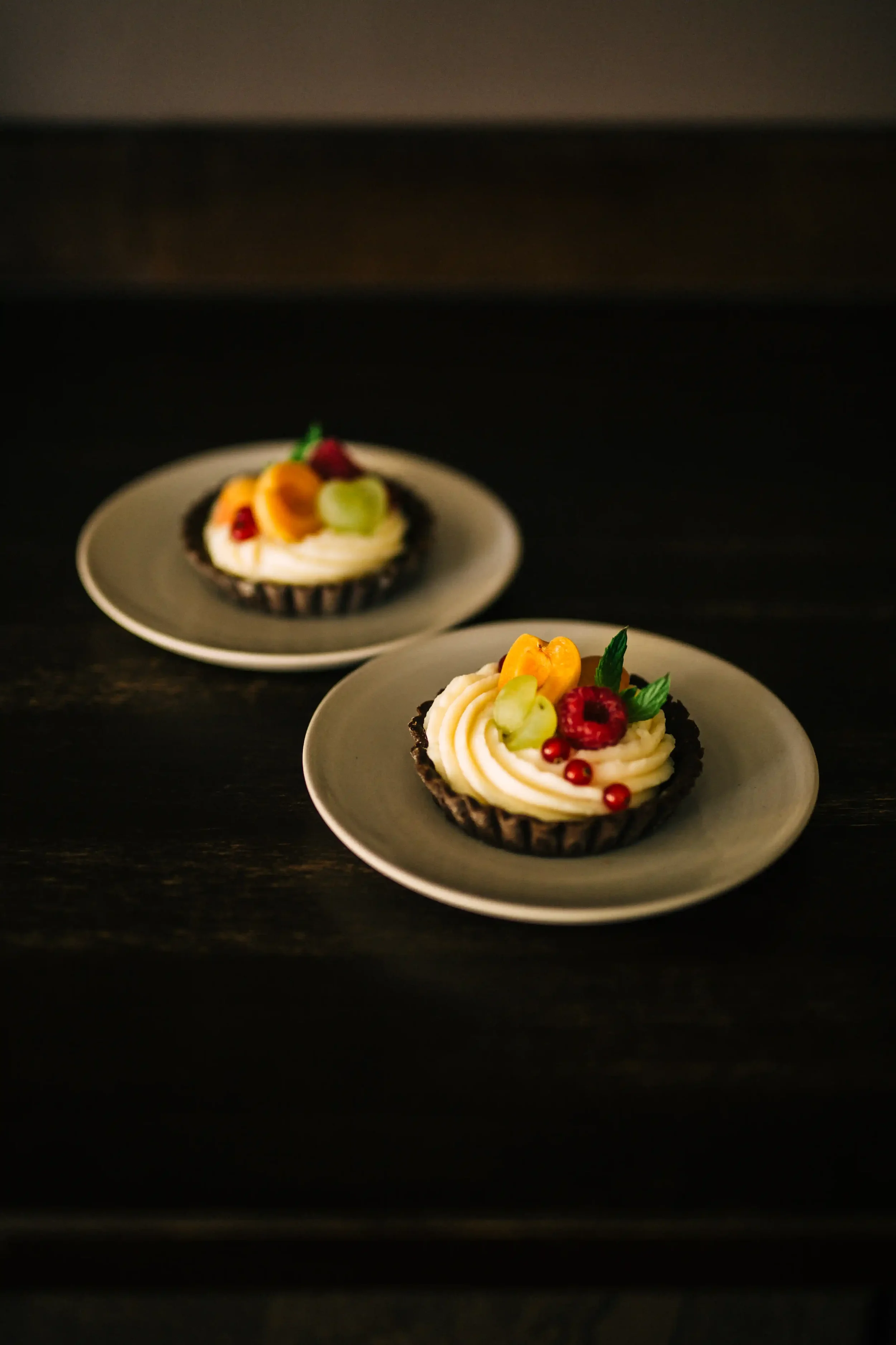 Two fruity cheesecake tartes with cream cheese frosting and seasonal fruit
