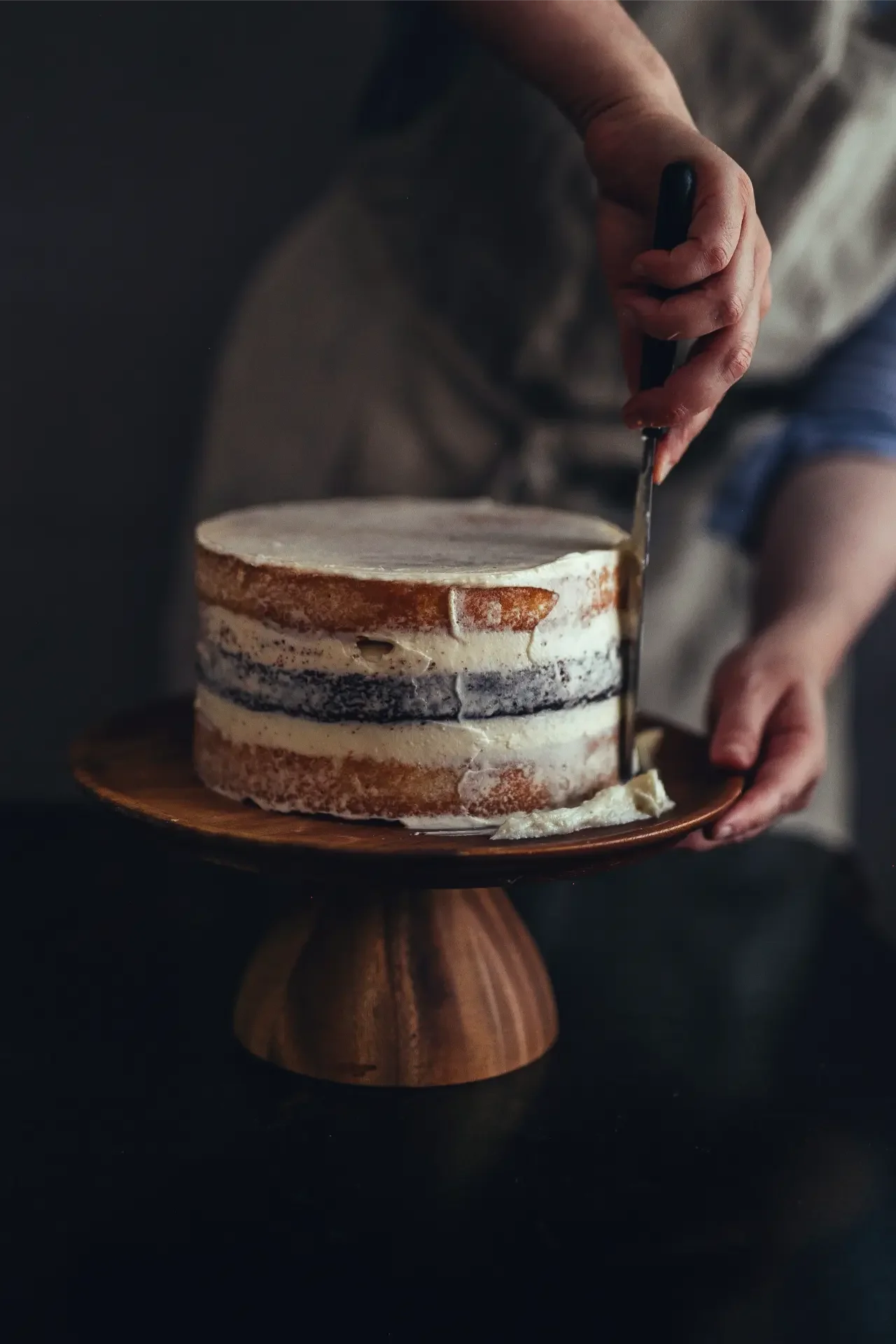 Frosting tahini cake on wooden cake stand