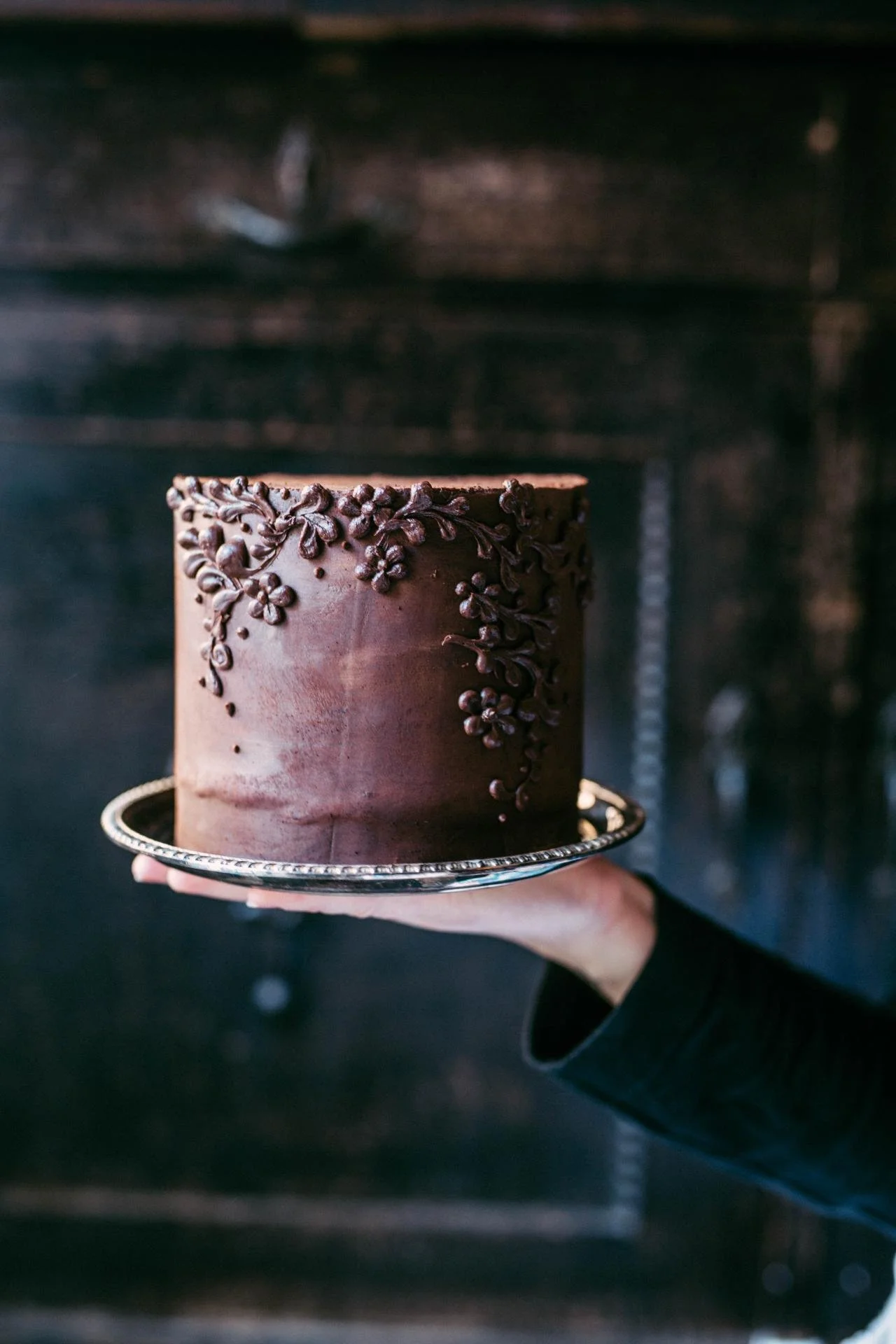 Minimal chocolate celebration cake with delicate frosting and decorative details