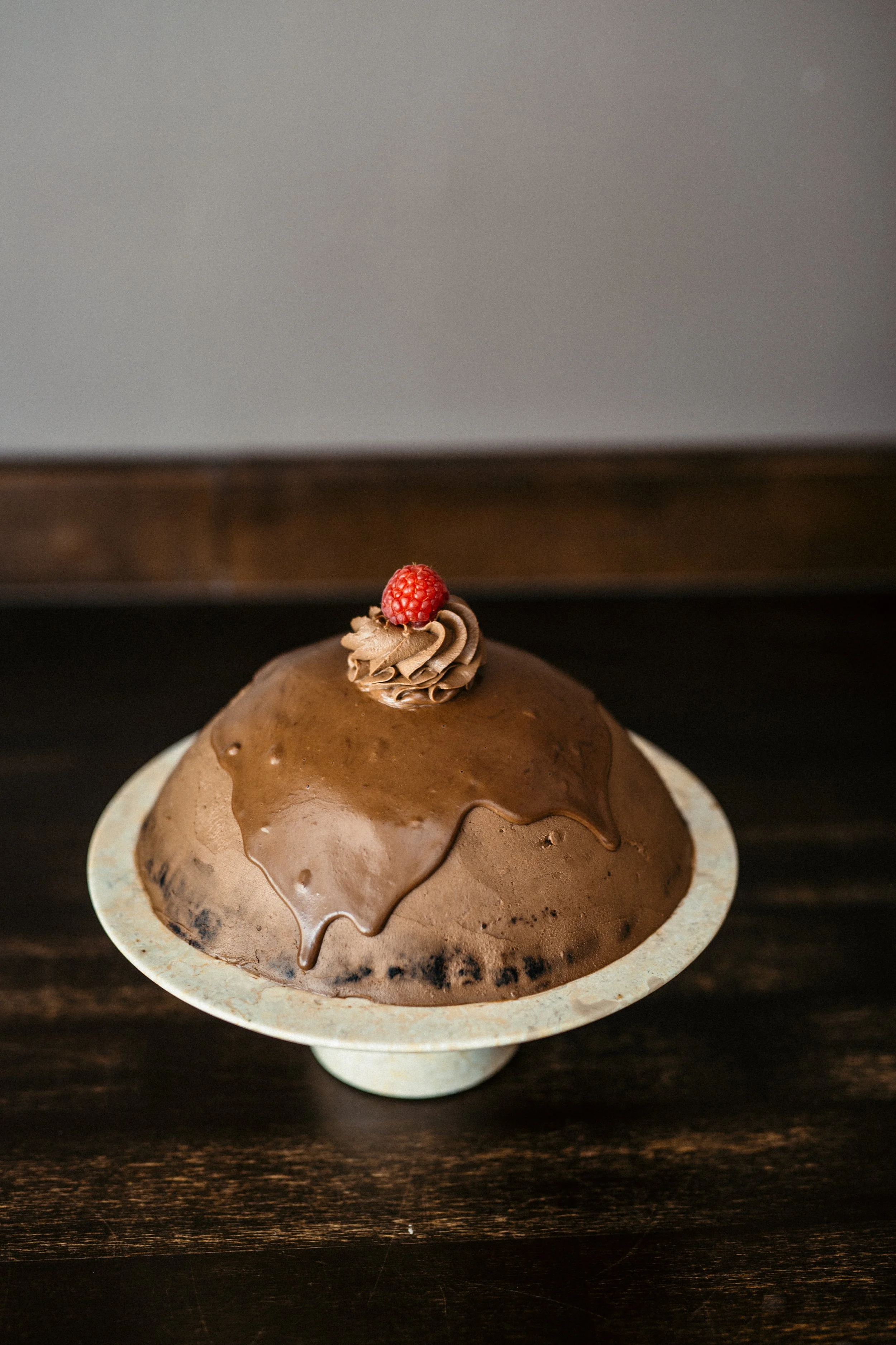 Chocolate birthday cake with piped chocolate frosting and a fresh raspberry