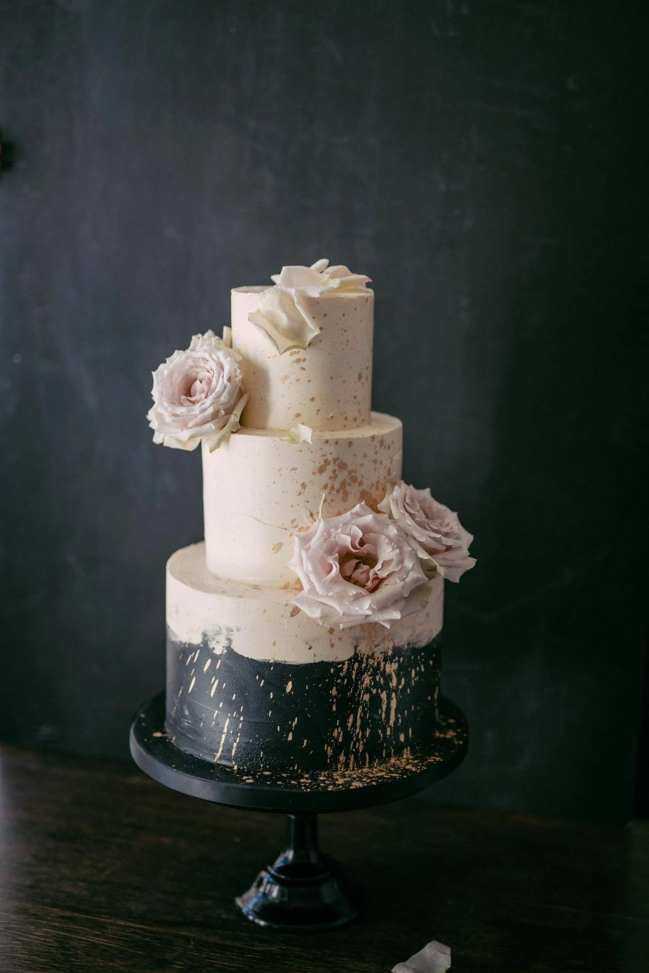 Three-tier white wedding cake decorated with soft pink sugar flowers and delicate details