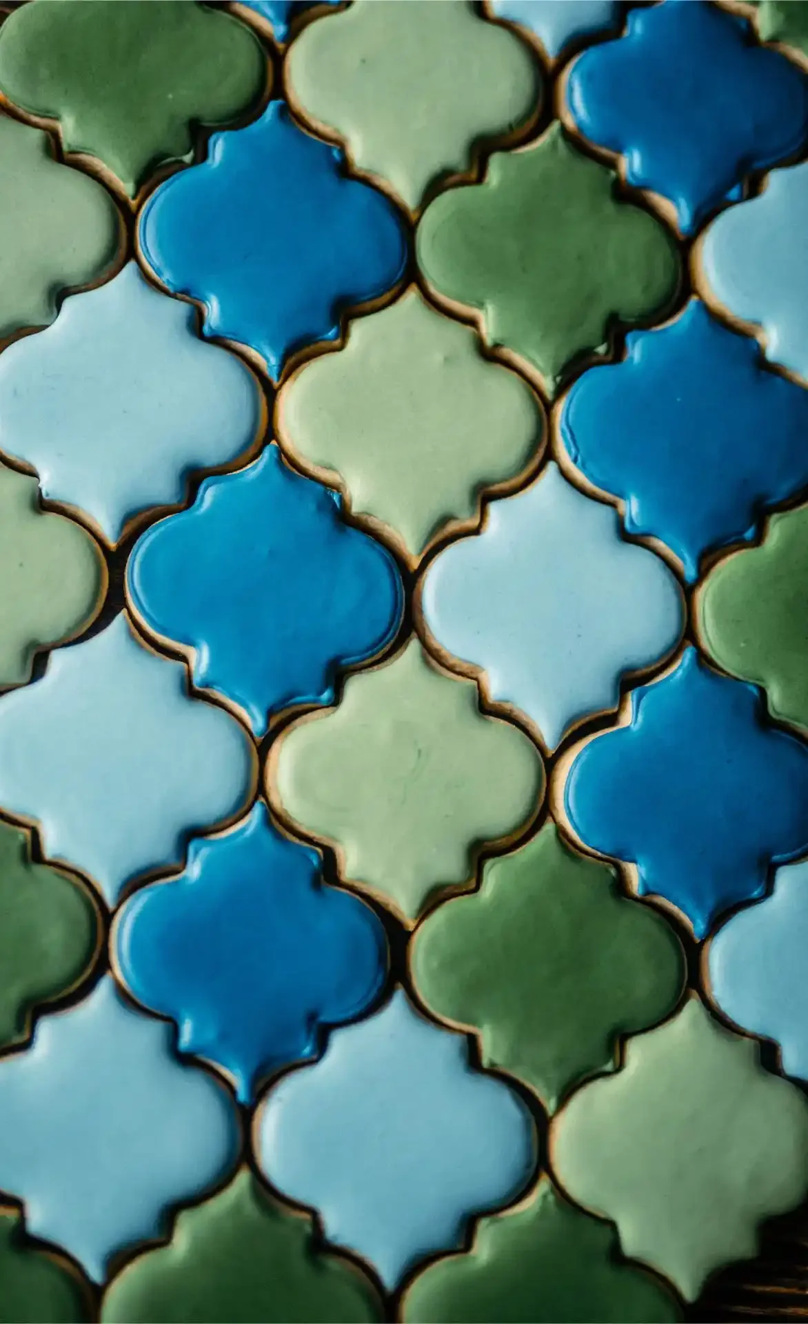 Colorful Moroccan-style tiles in green, blue, and teal with gold edges.
