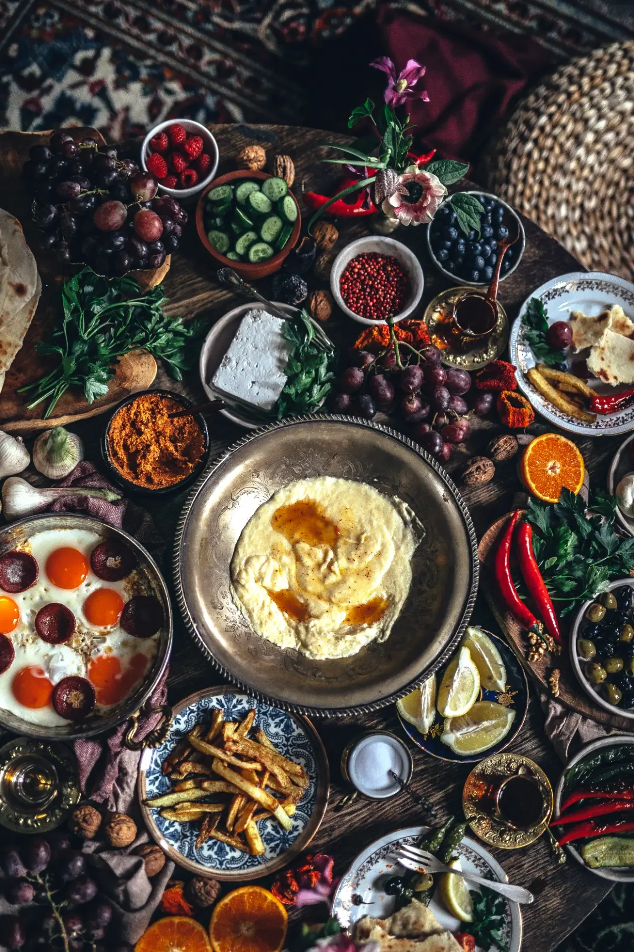 Warm hummus topped with olive oil surrounded by colorful Mediterranean side dishes
