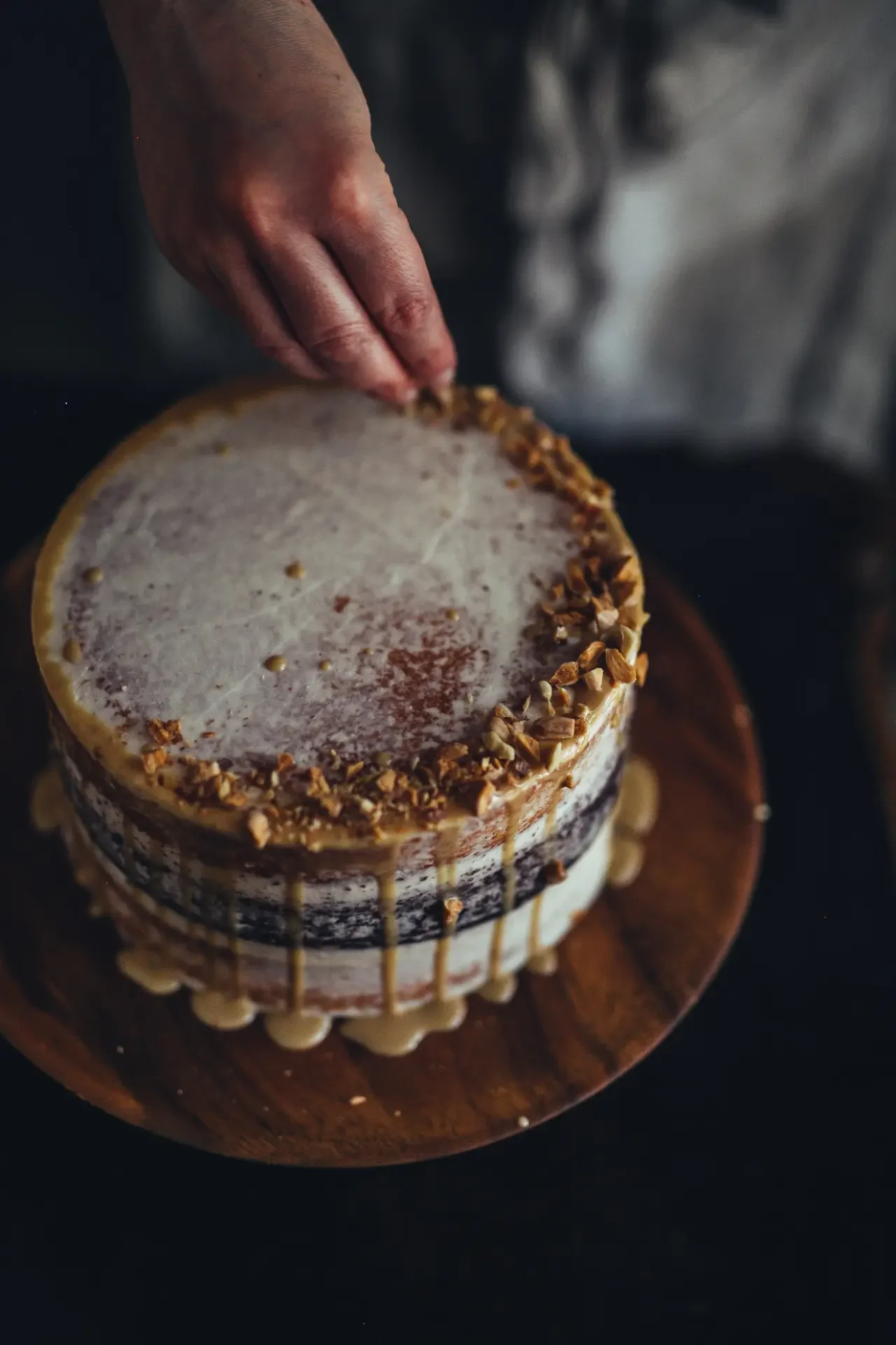 Finishing tahini cake topped with nuts