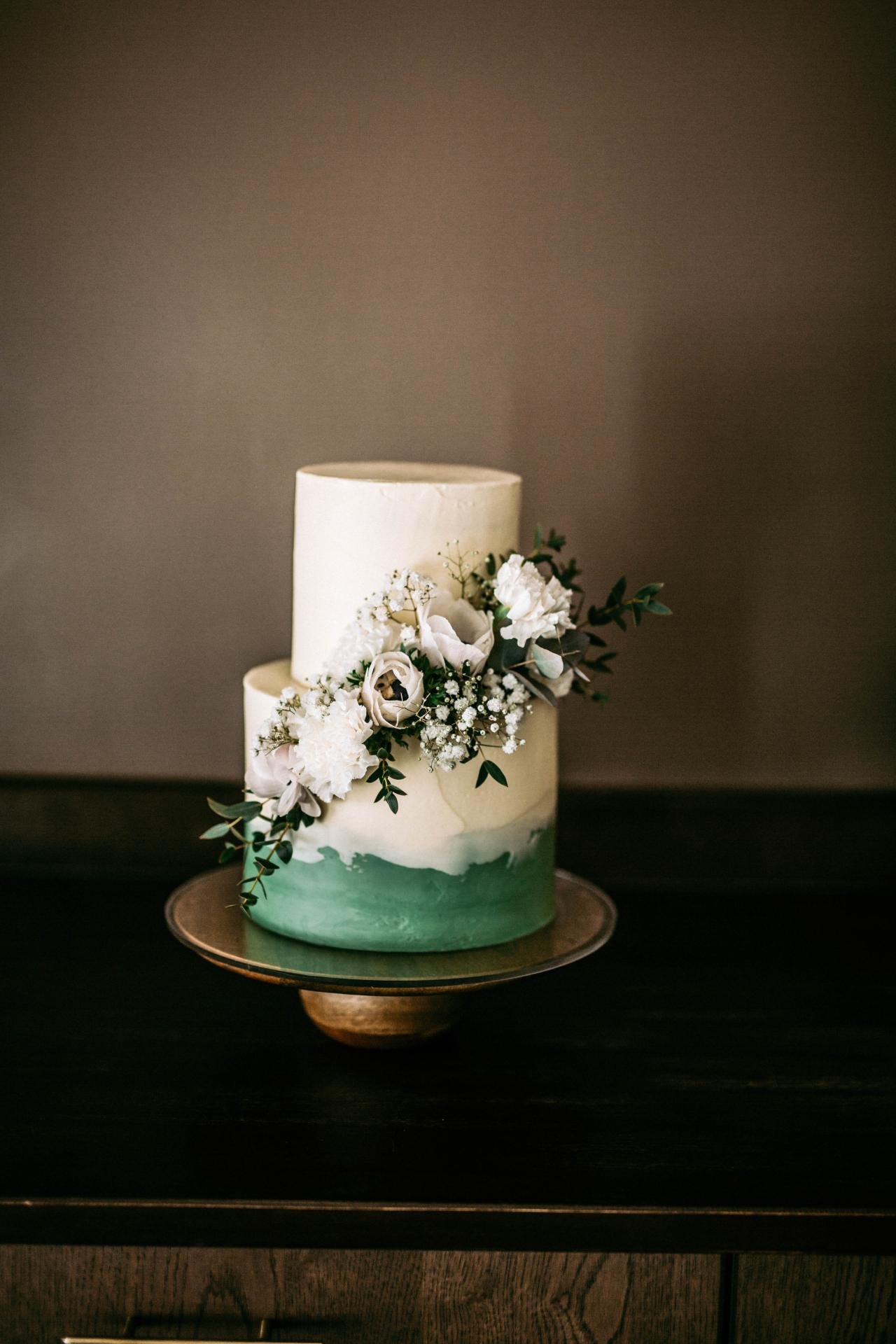 Elegant two-tier wedding cake with cascading white flowers on a wooden cake stand