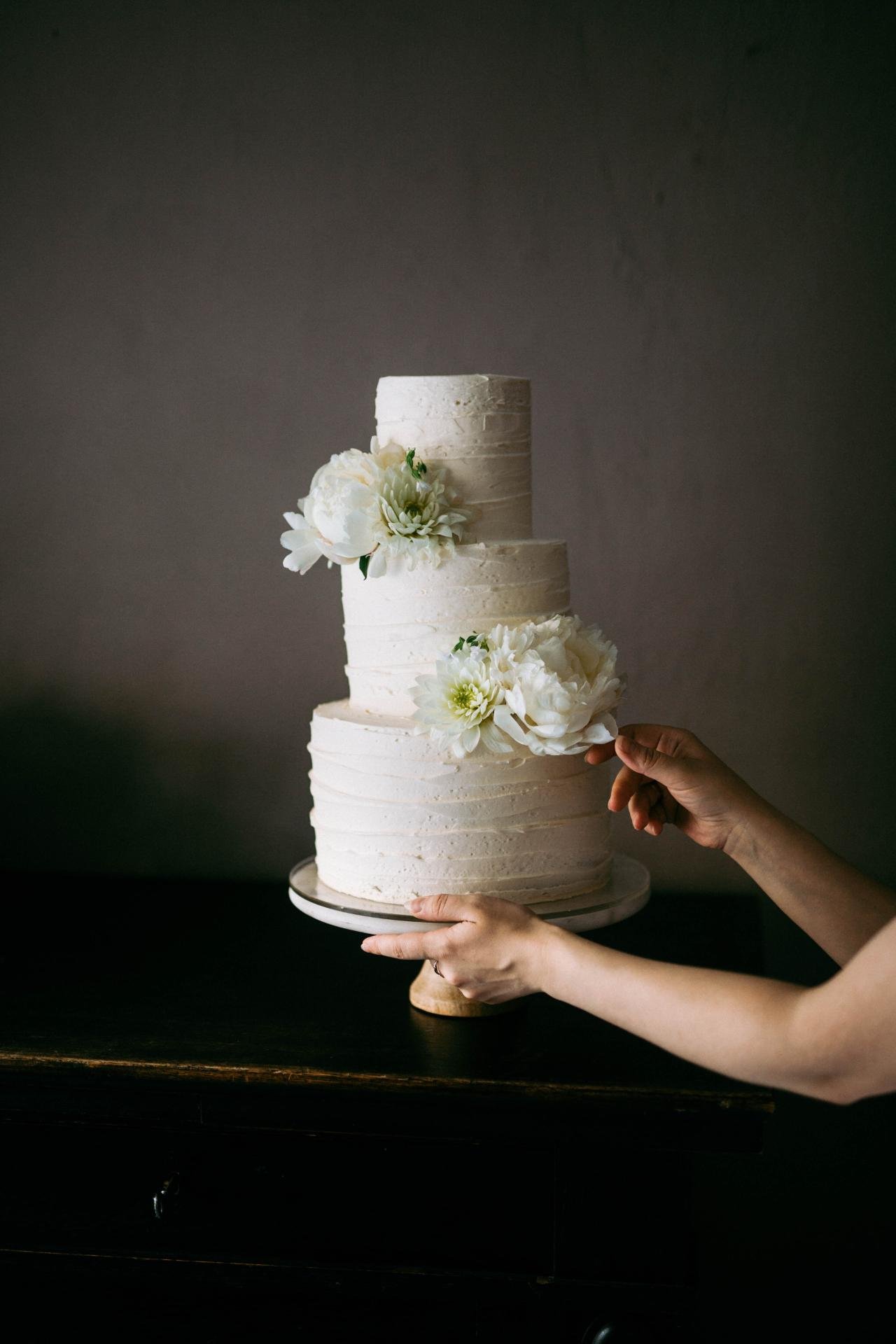 Elegant white tiered wedding cake with delicate green and white floral decoration