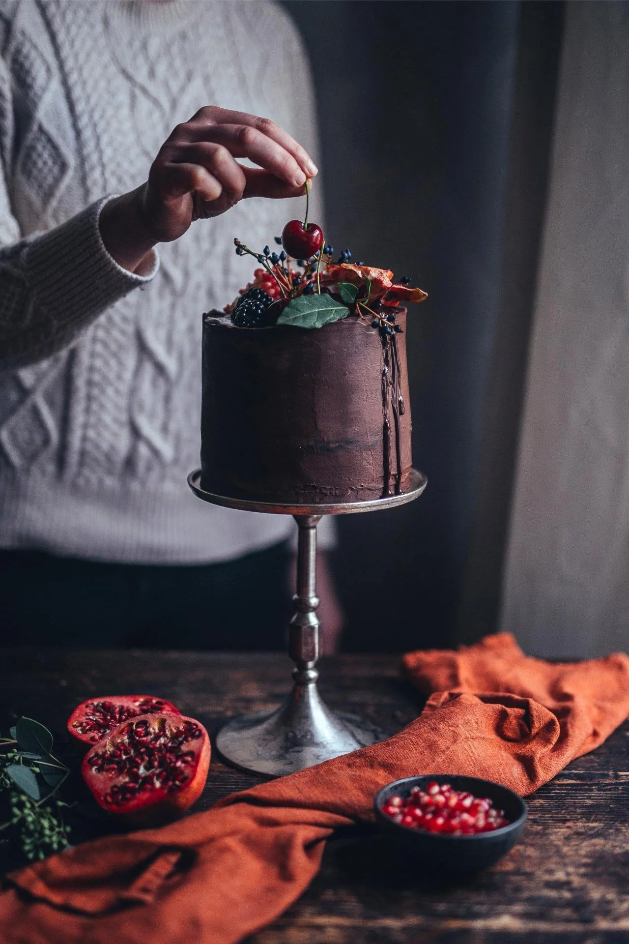 Dark chocolate birthday cake with fresh berries being decorated by hand