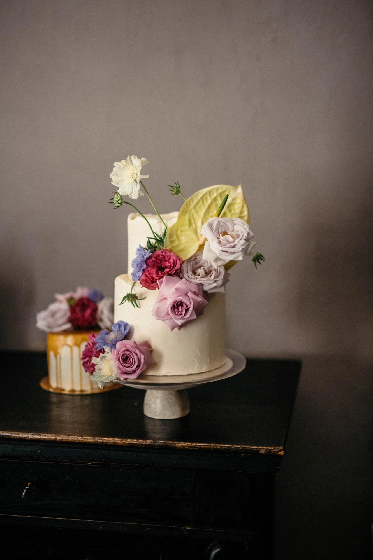 Romantic wedding cake decorated with fresh pink, purple and white seasonal flowers