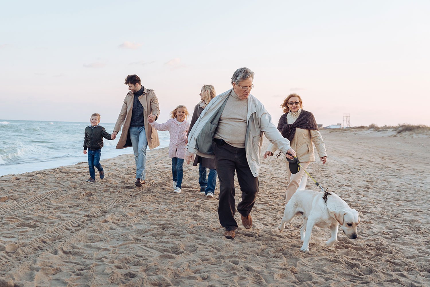 multi-generational family on the beach with their dog at sunset