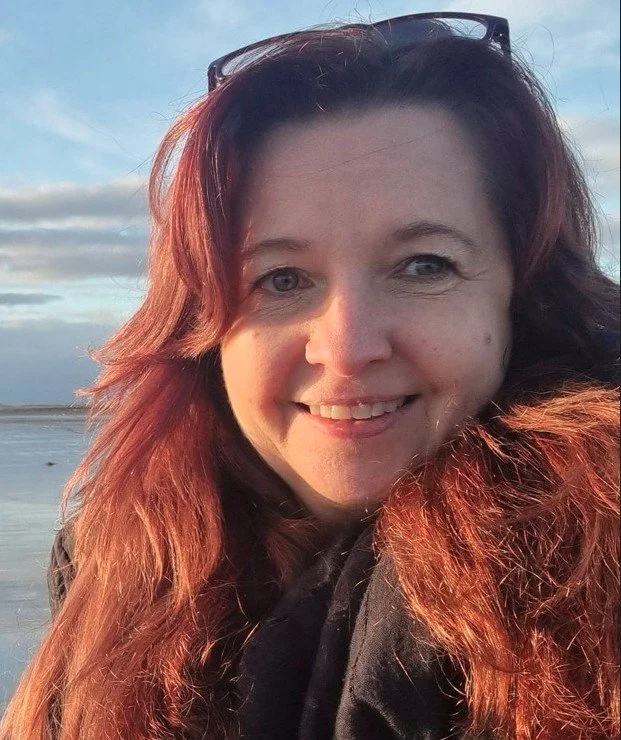 Selfie of woman smiling to camera with cloudy sky and beach in background