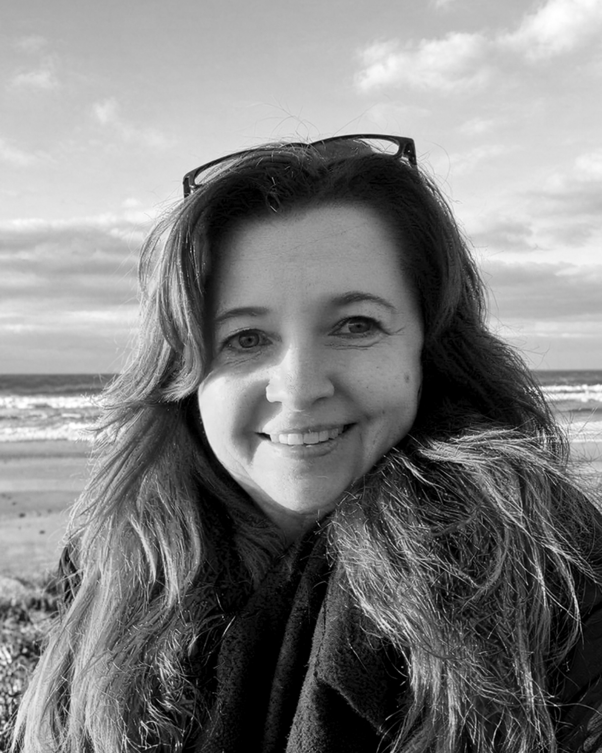 Selfie of woman smiling to camera with cloudy sky and beach in background