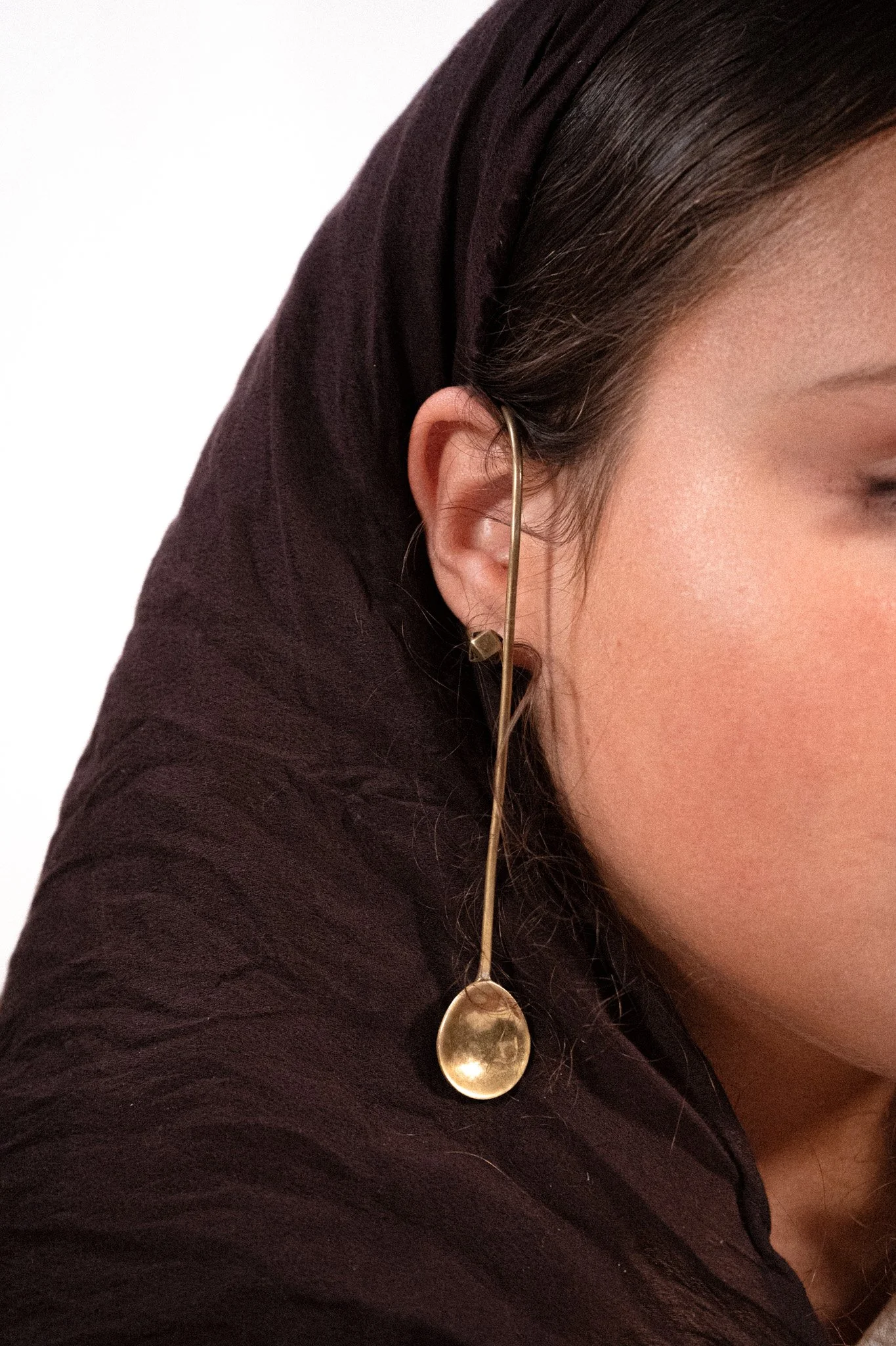 Une femme porte une boucle d'oreille en forme de cuillère suspendue.
