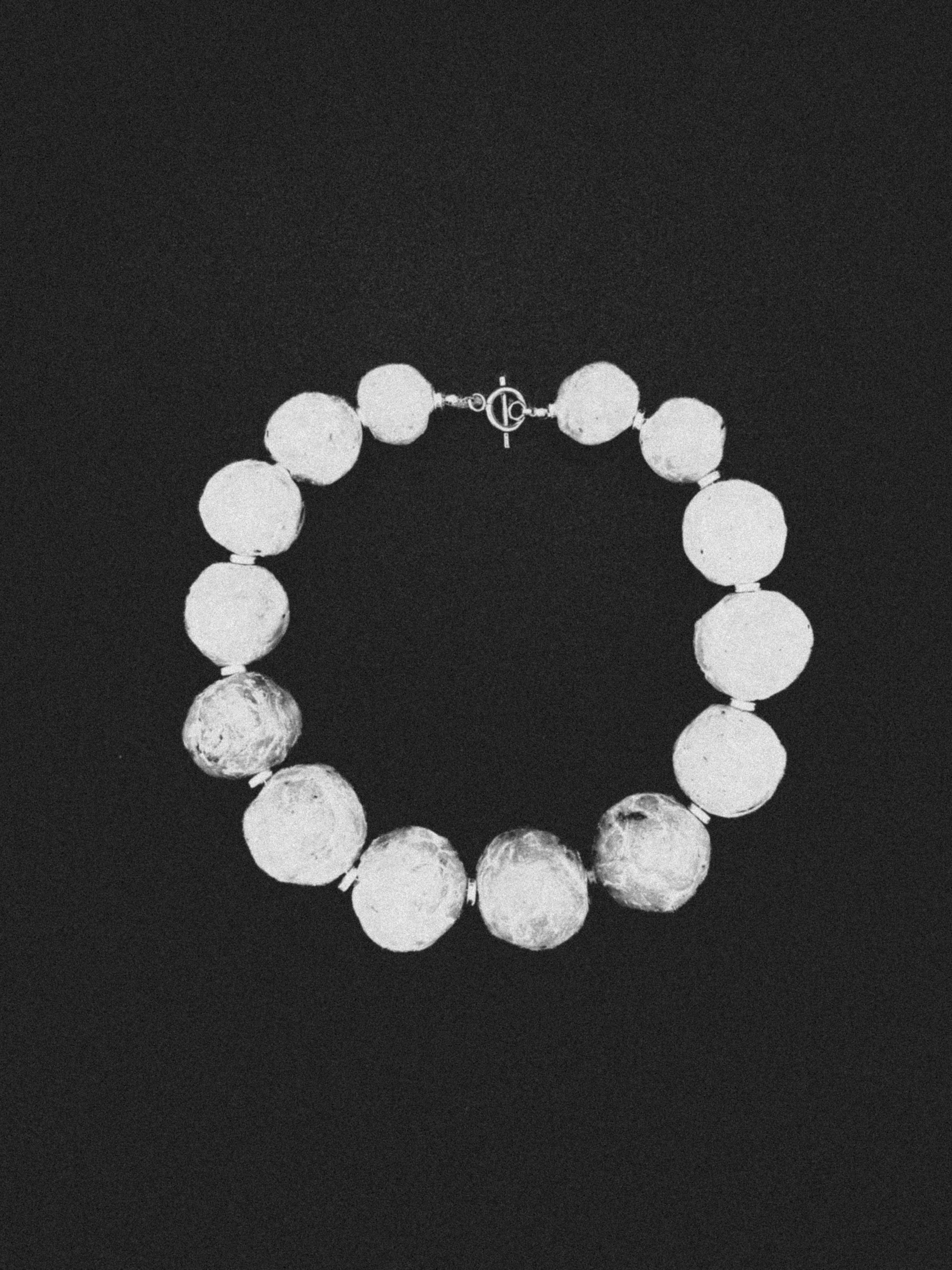 Bracelet en forme de cercle composé de différentes phases de la lune en relief, avec fermeture en métal.