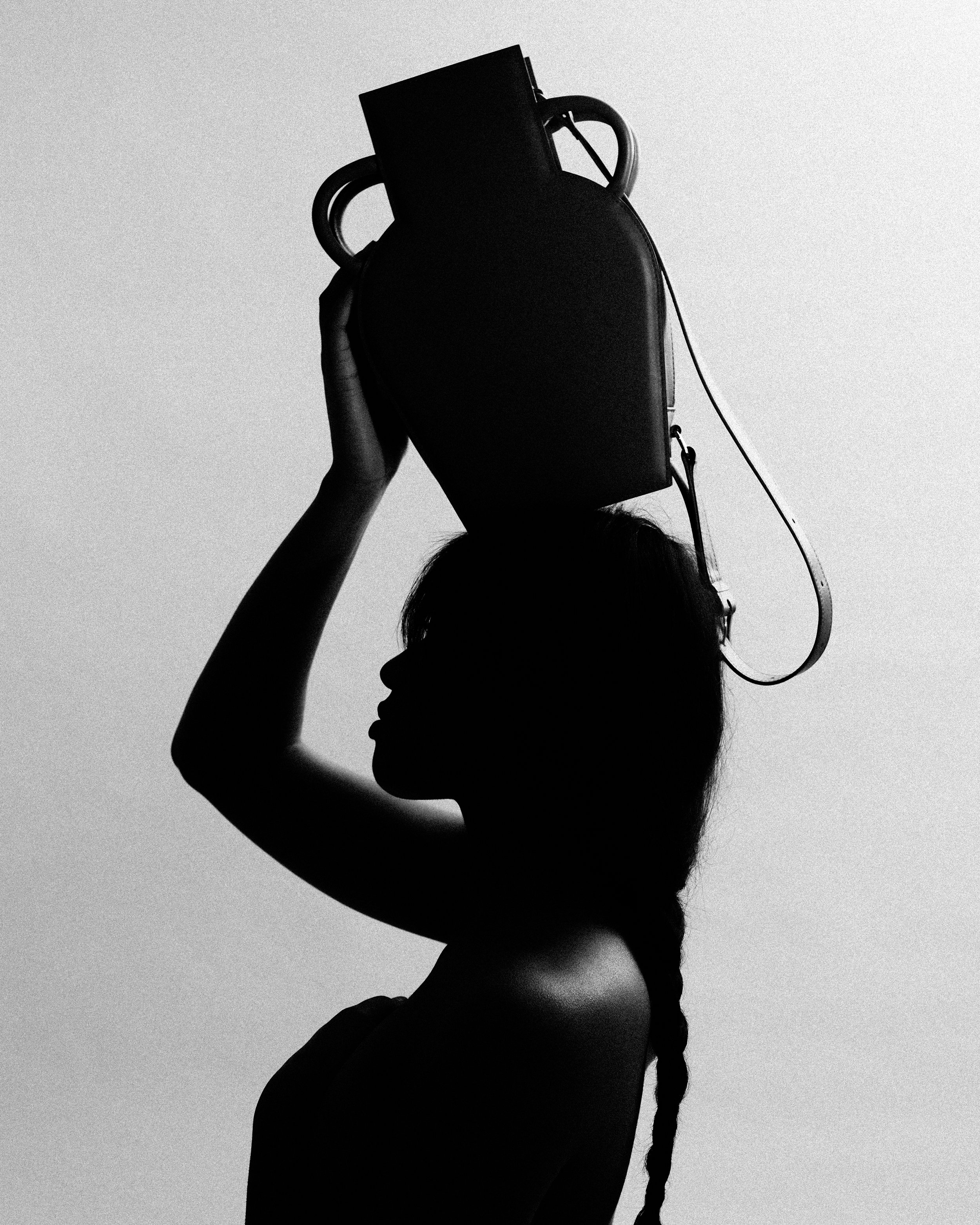 Silhouette d'une femme portant un sac à main sur la tête