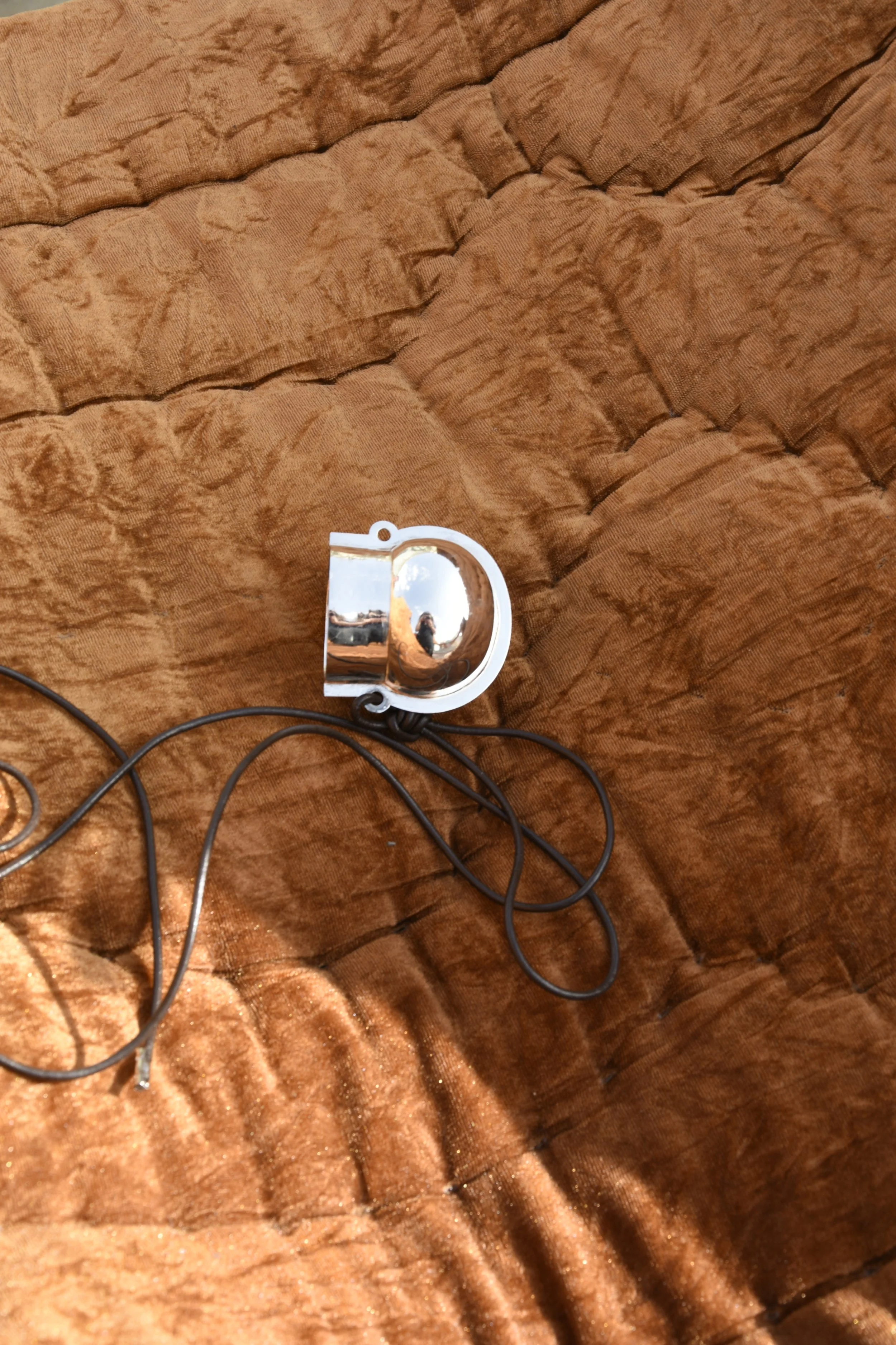 Une petite clé USB avec un symbole de super héros (Superman) en chrome sur un lit en tissu marron