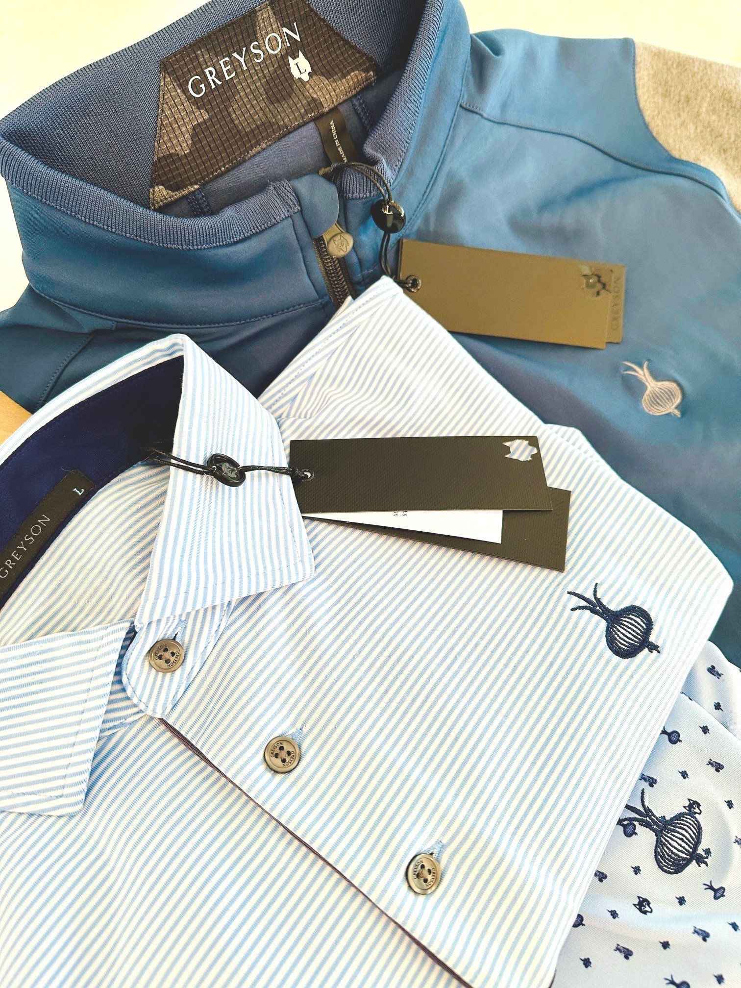 Neatly folded golf apparel from luxury brands featuring elite golf club logo. Part of a pro shop merch series by ProShopper