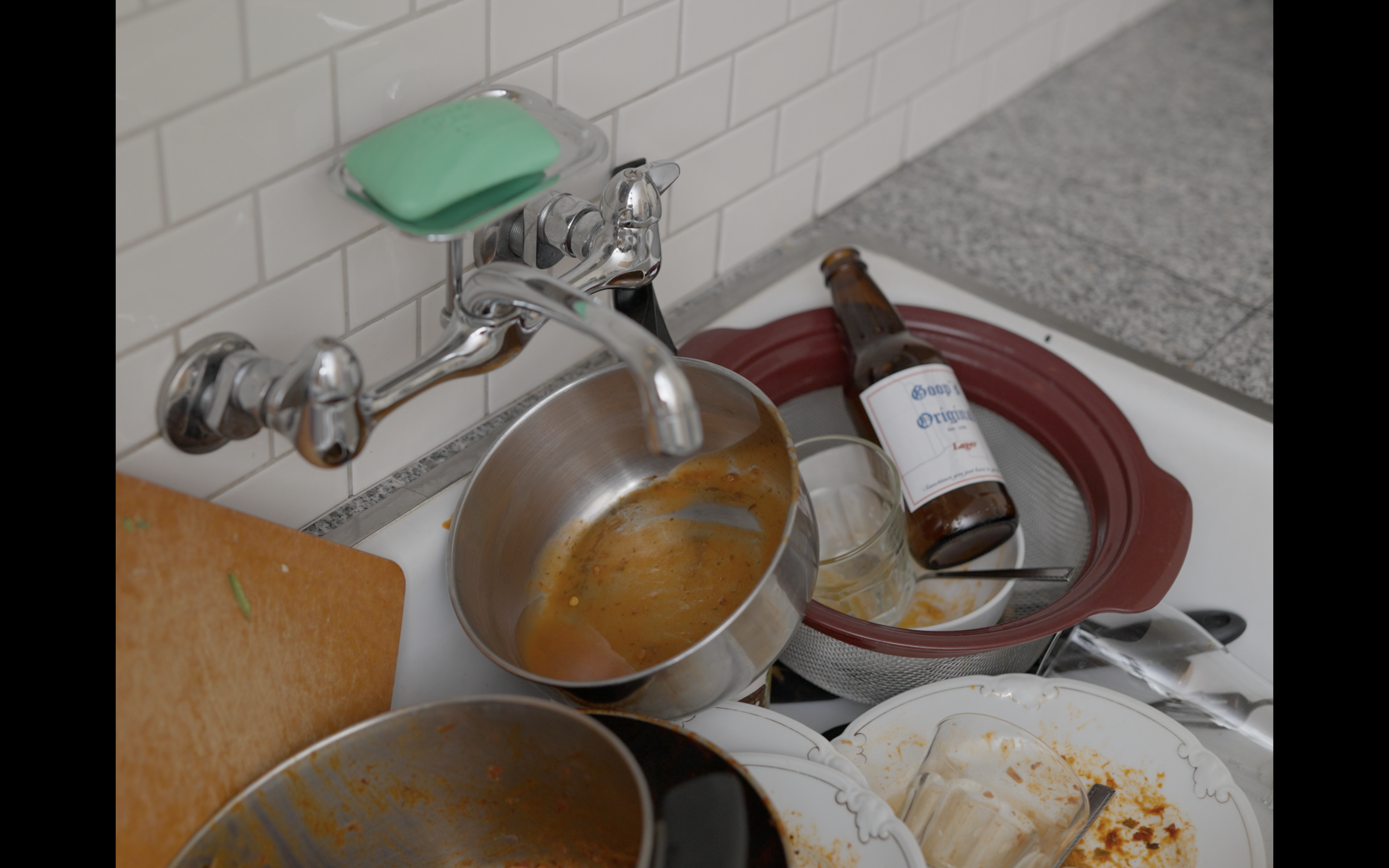 THE KITCHEN is charming but messy, Pink dish gloves sit near the shore of the stale sink, heavy with dishes.