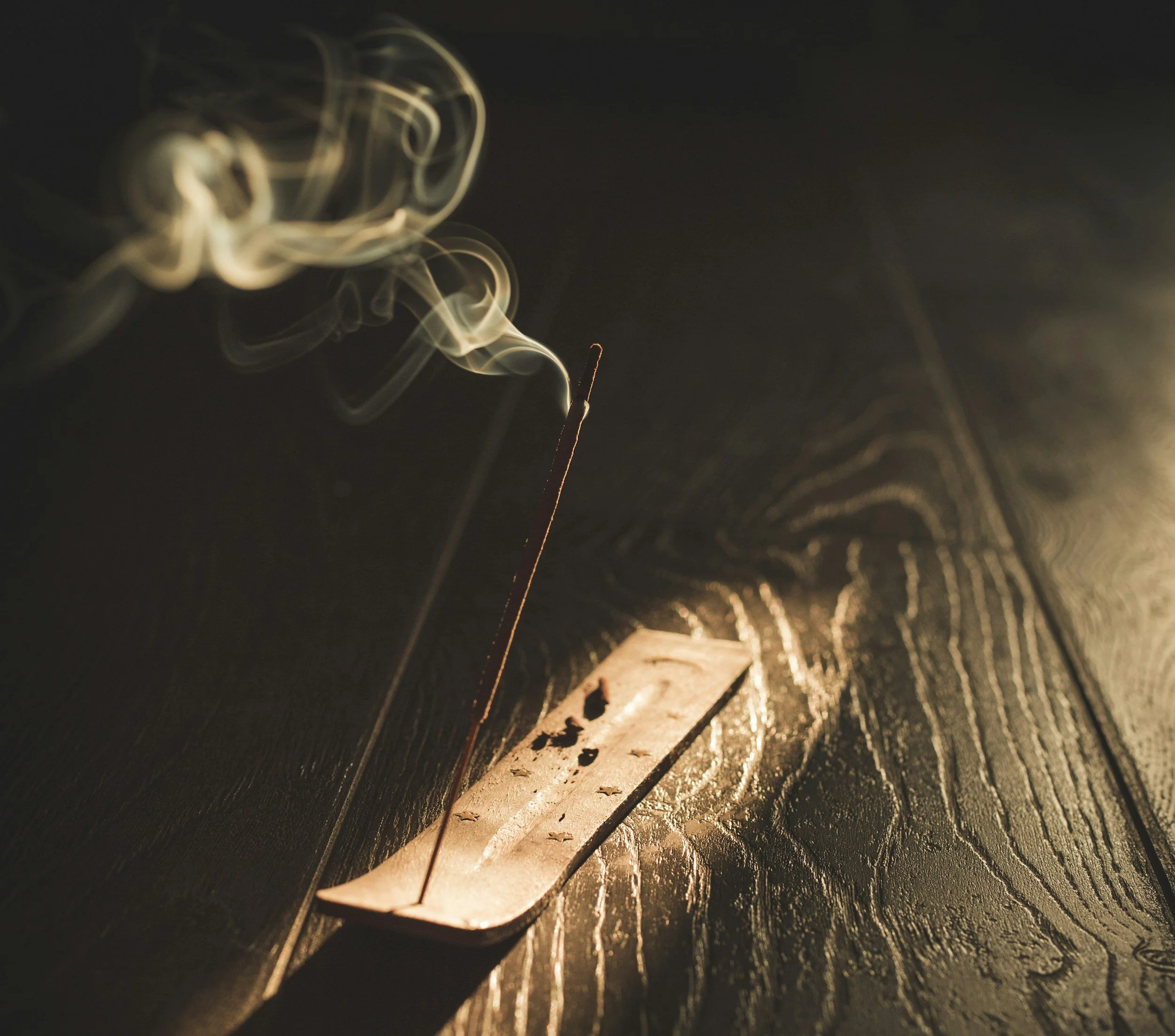 Close-up of a burning matchstick releasing sparks and smoke against a dark background.