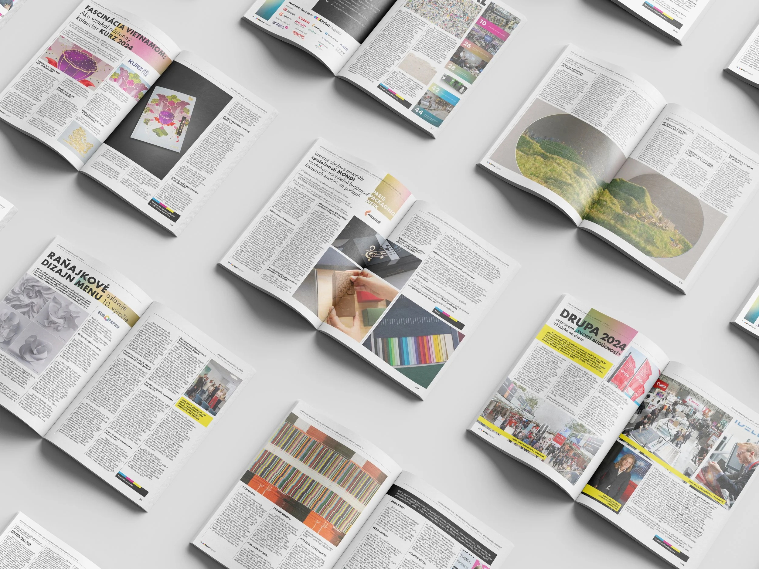 Various open newspapers spread out on a light surface, showing articles, images, and advertisements.