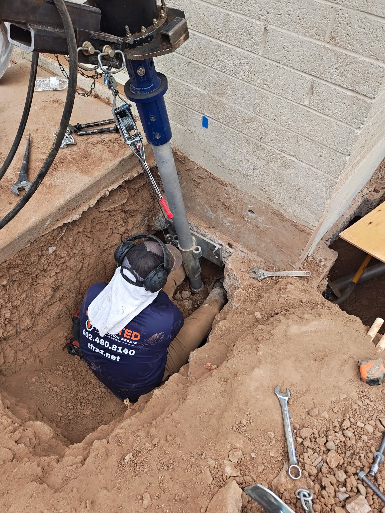 Picture of Steel helical piers getting screwed deep into stable soil to level foundation.