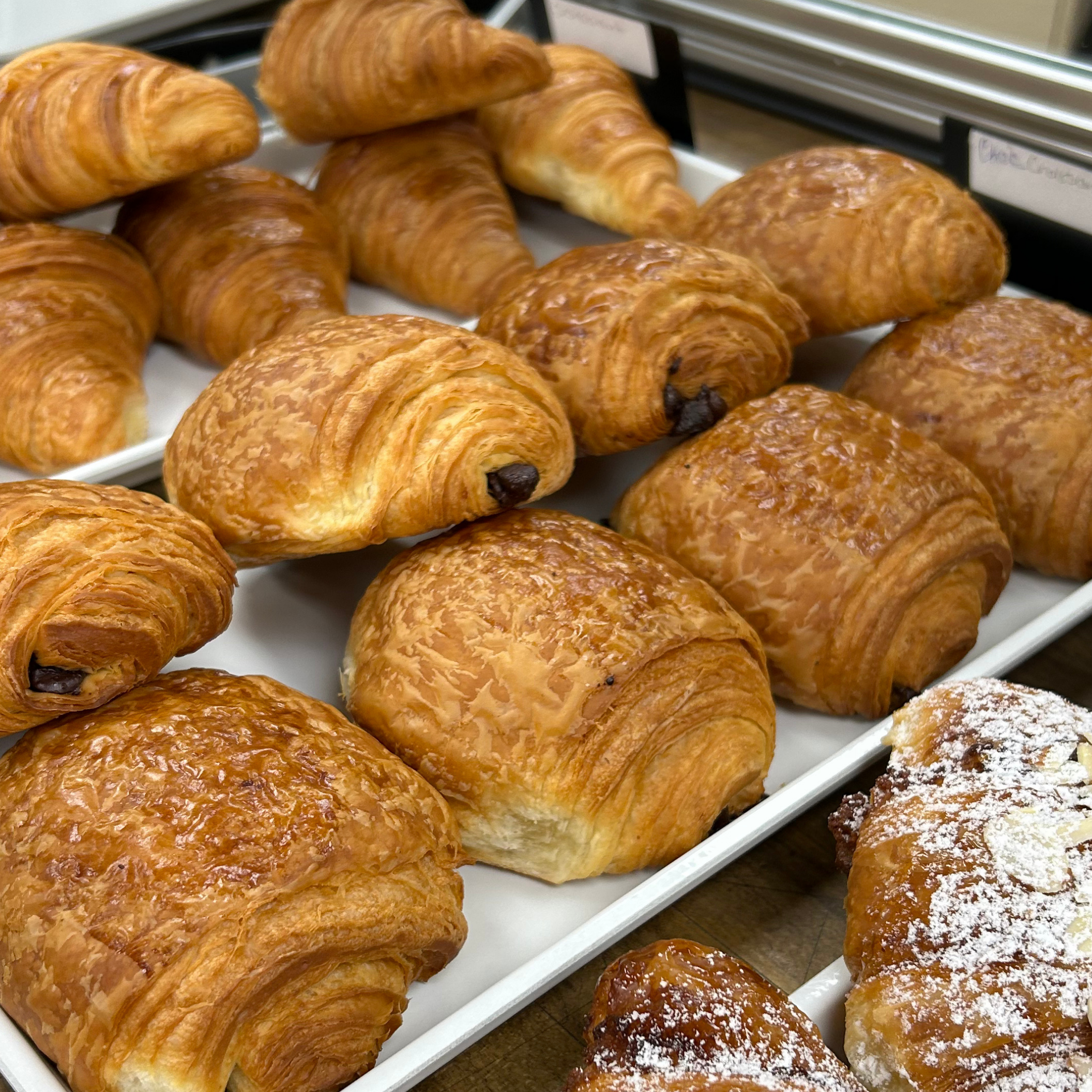 rows of stacked croissants, chocolate croissants, and the edge of an almond croissant