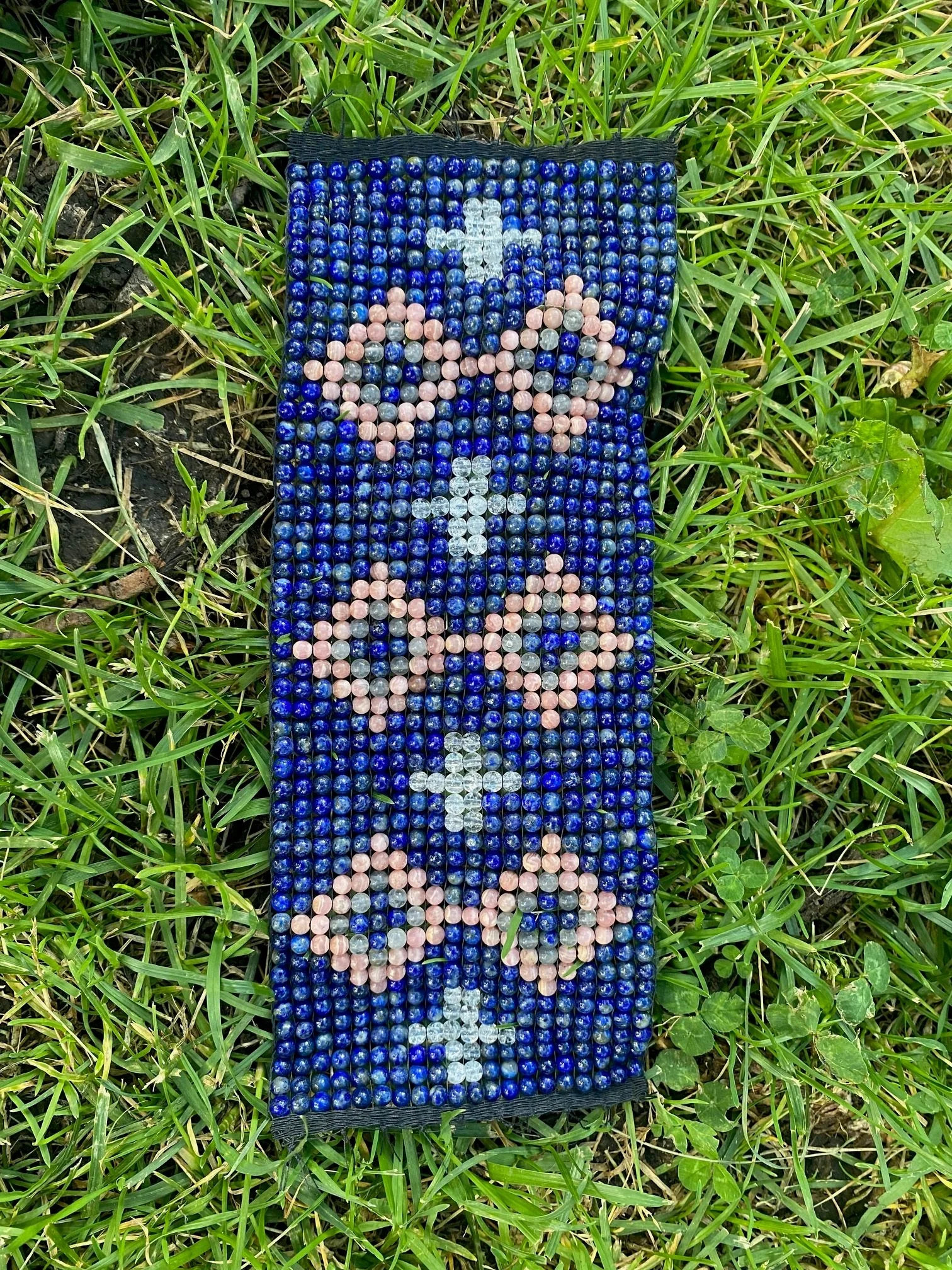 Bead-woven textile panel composed of deep blue and pink beads forming repeating floral motifs with cross shapes.