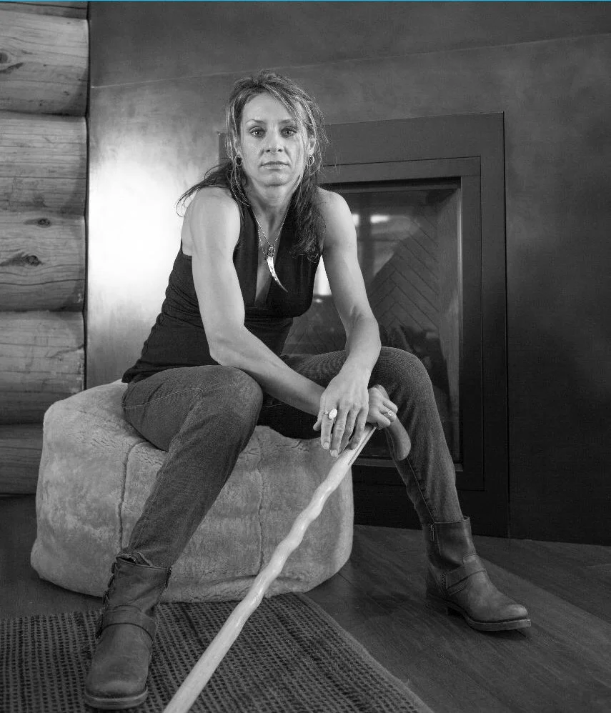 Leah Potts sits on a round ottoman in a moody black and white portrait photo