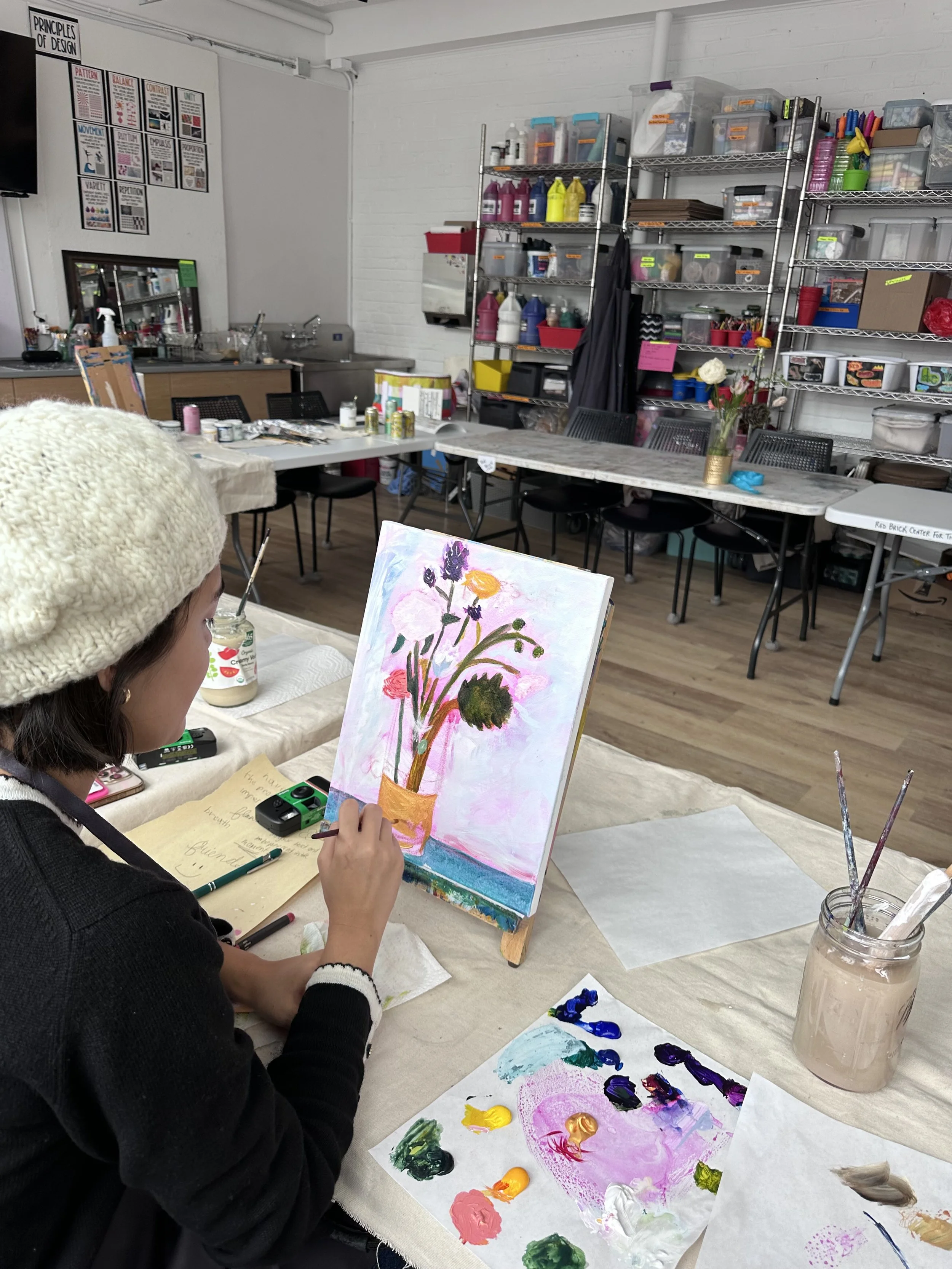 woman painting a flower vase on canvas