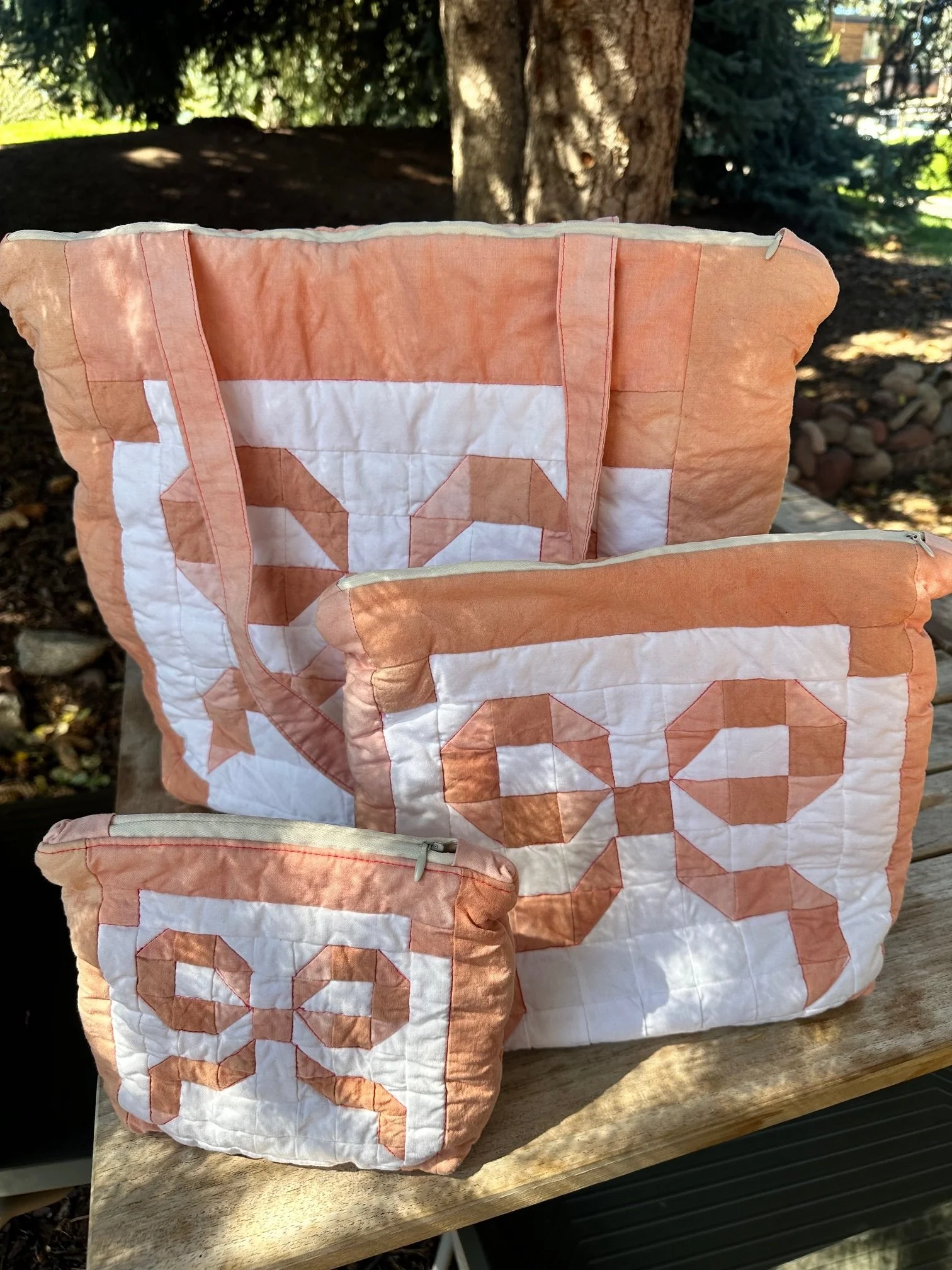 Set of quilted textile bags in peach and white fabric featuring geometric patchwork designs and soft sculptural forms.