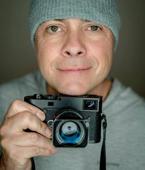 Head shot of Dan Bayer holding a camera close to his face