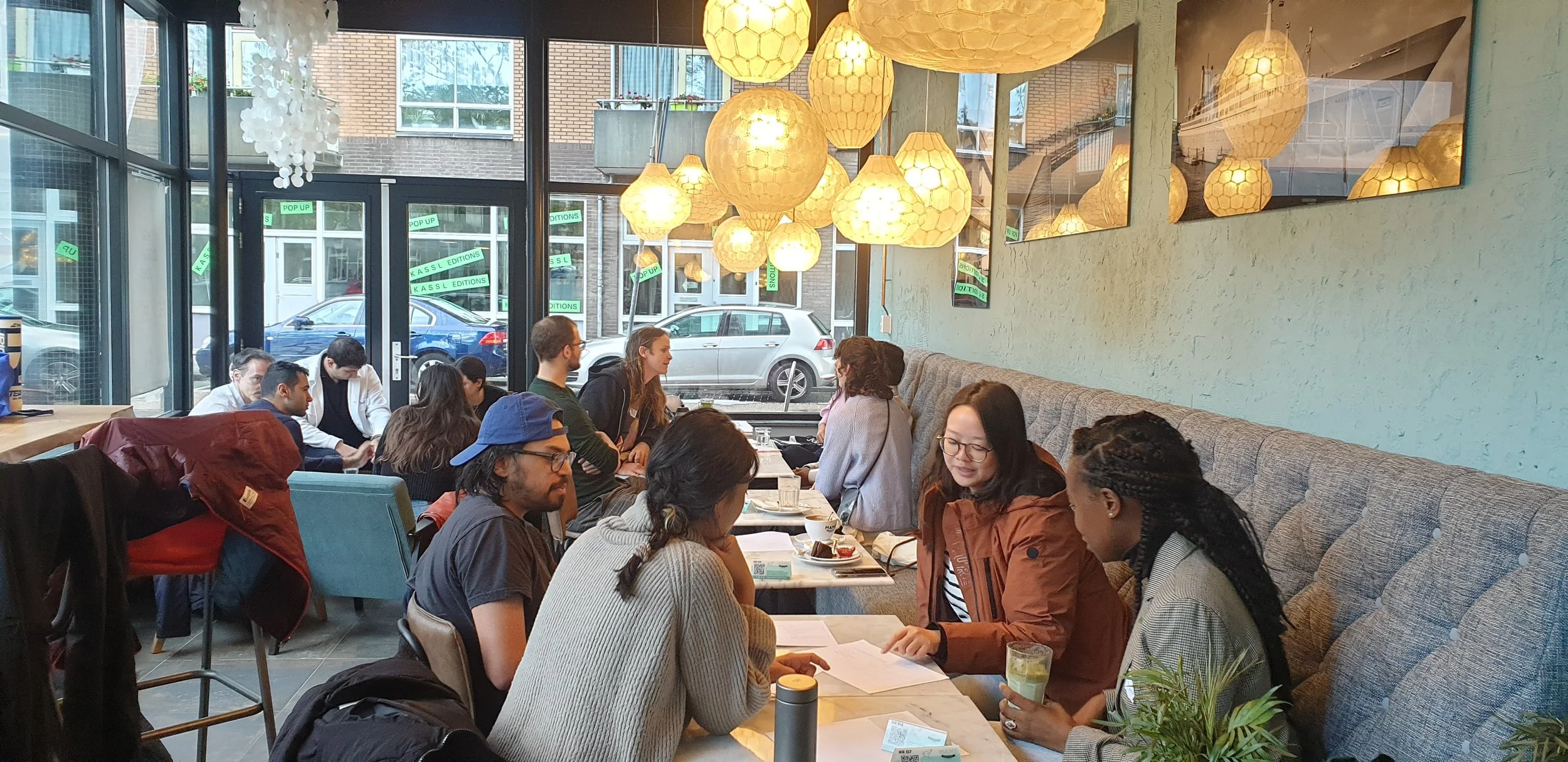 Group members sitting at tables inside a cafe  in a coaching session of Secure Attachment Group Coaching