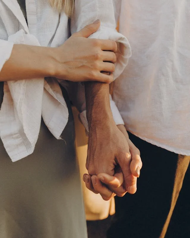 Close-up of a woman holding the hand of an elderly person.