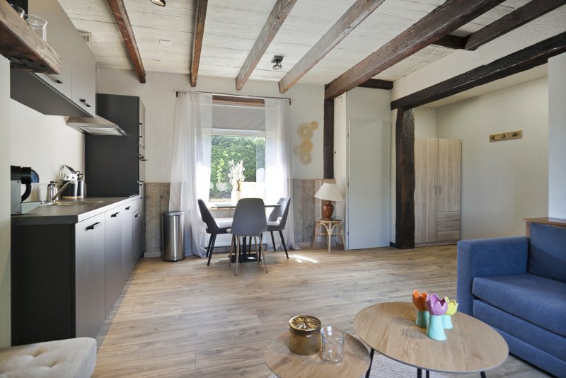 Woonkamer met keuken, eettafel, bank en decoraties in een landelijke stijl van het 2 persoon vakantiehuis te huur bij Paal.
