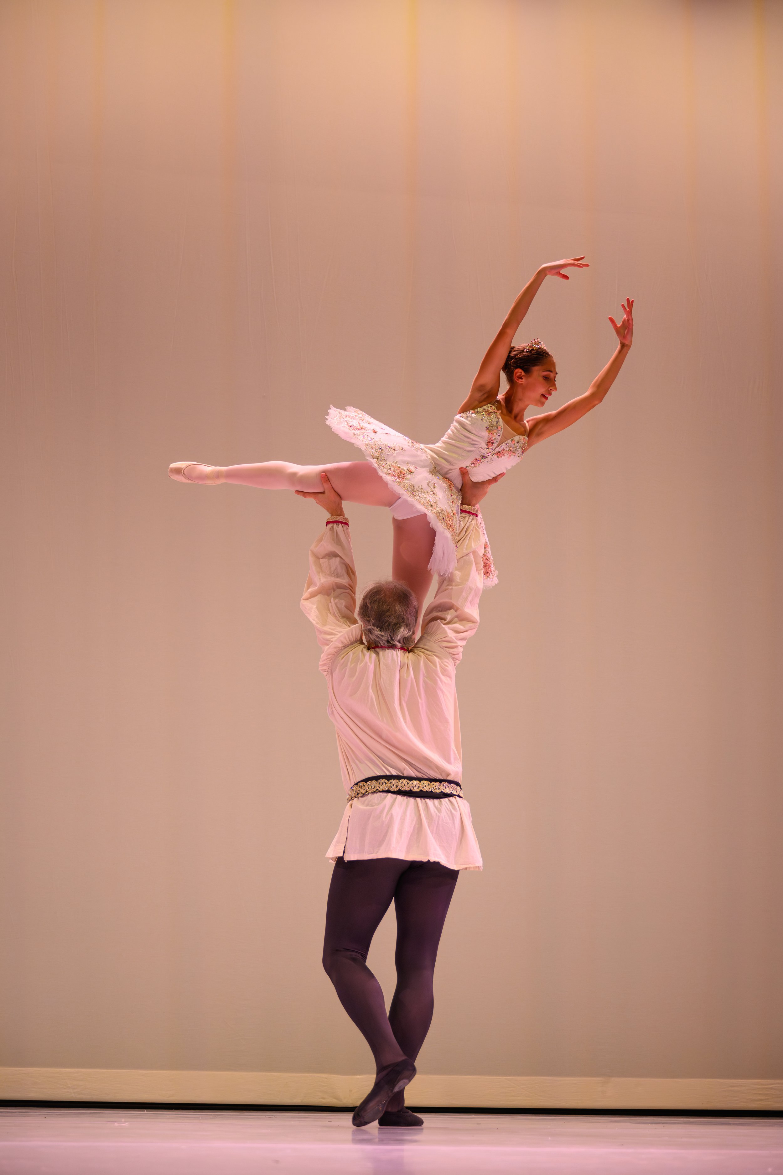 Ballet dancers performing on stage with a male dancer lifting a female dancer in a pose.