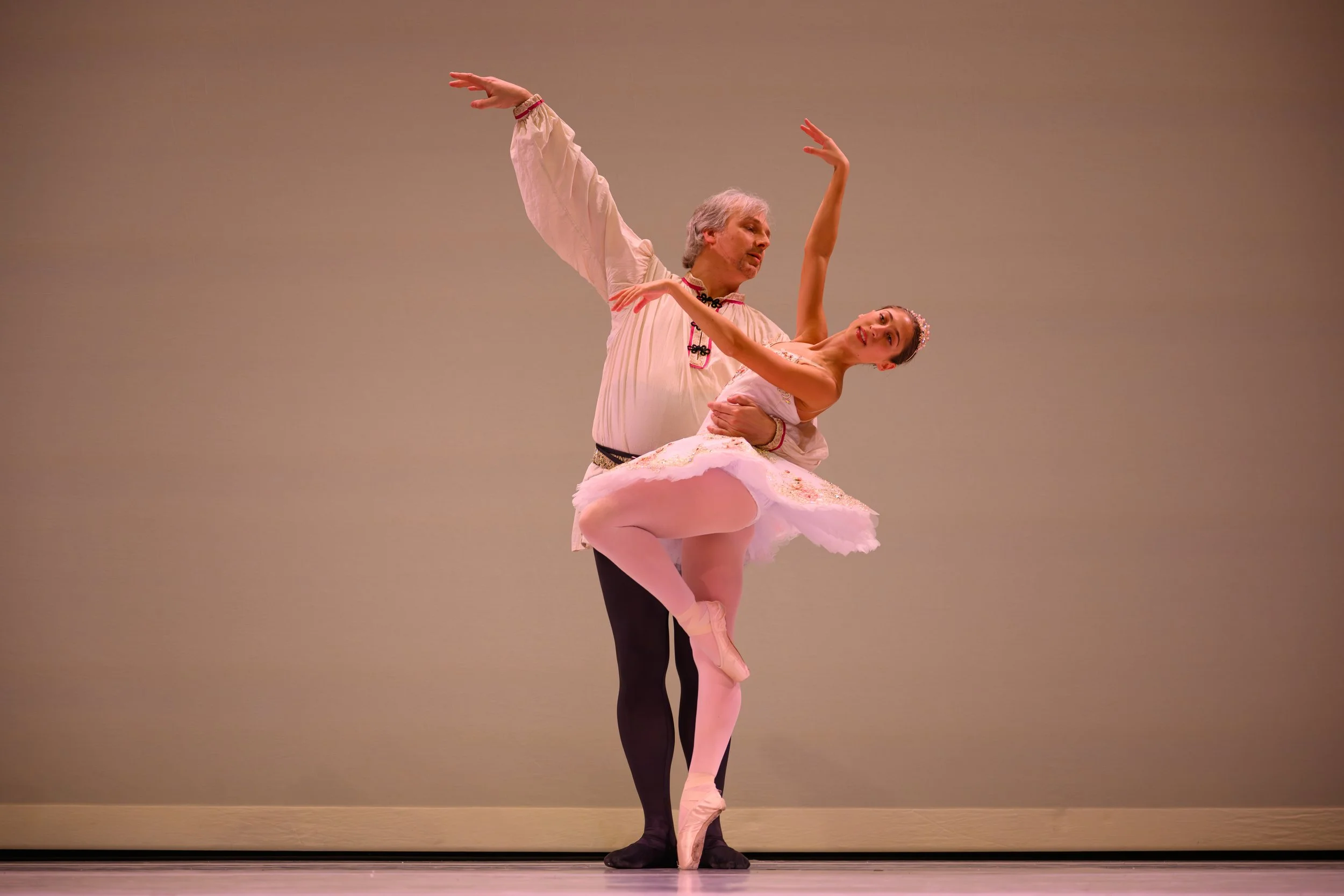 Ballet dancers performing on stage, with one male dancer lifting a female dancer who is en pointe.