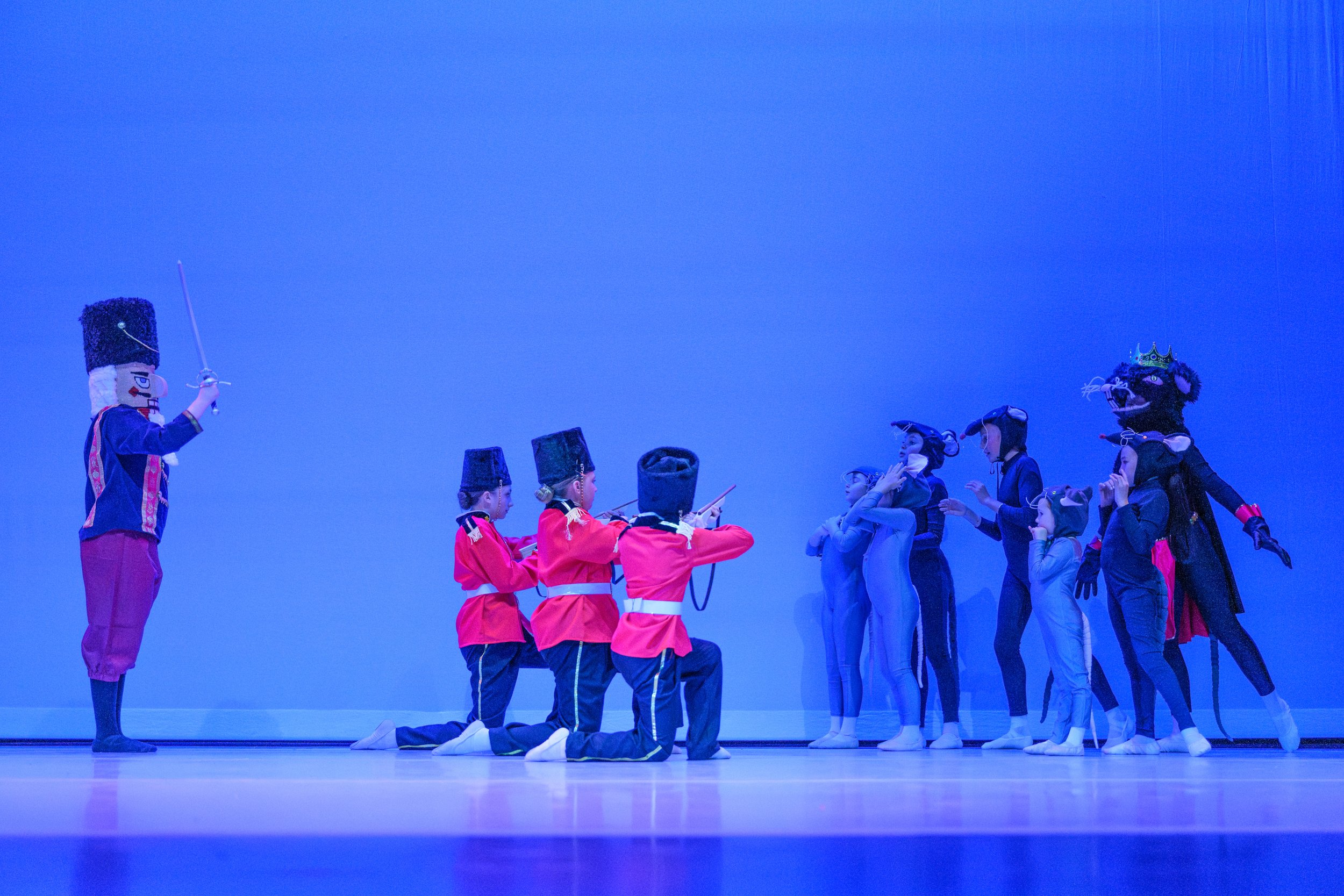Children dressed as soldiers and animals performing on stage in a theatrical play.