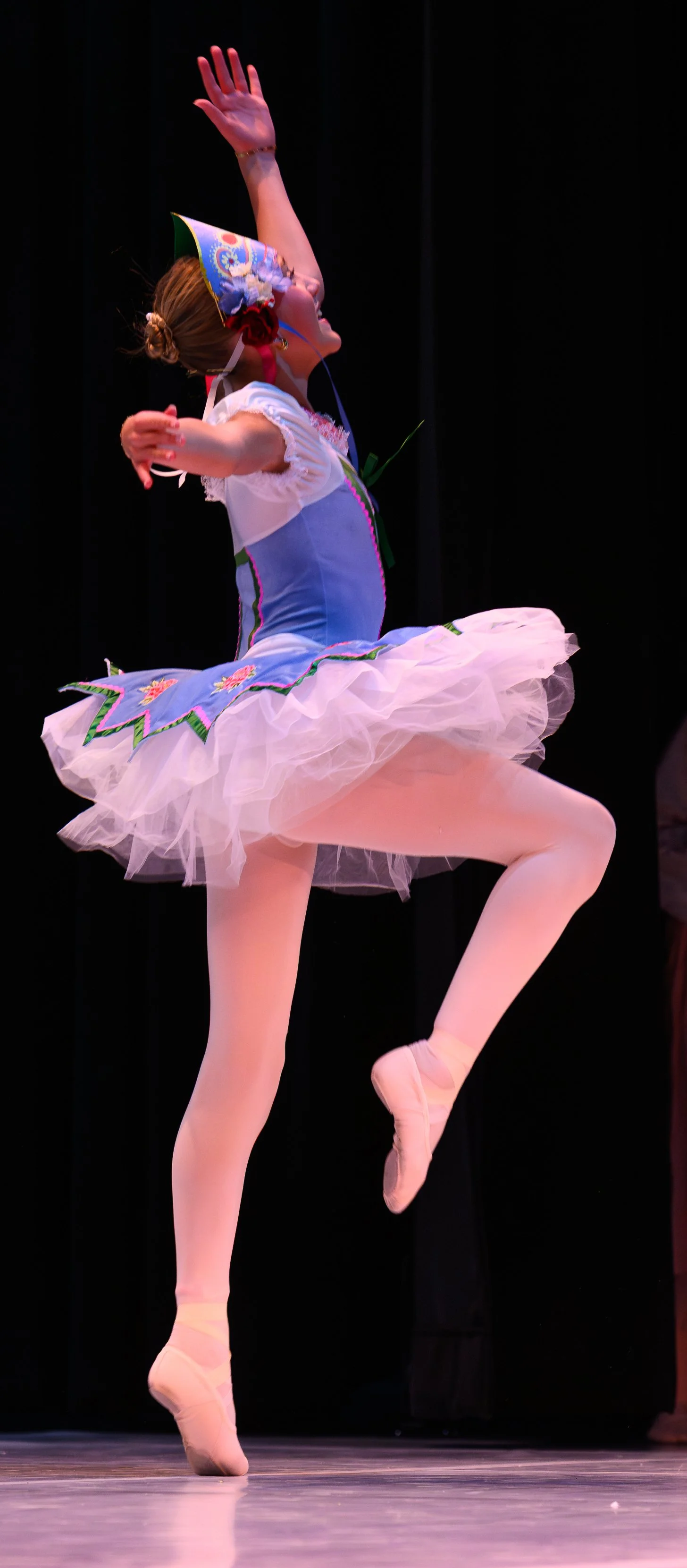 Ballet dancer in a colorful costume performing on stage.