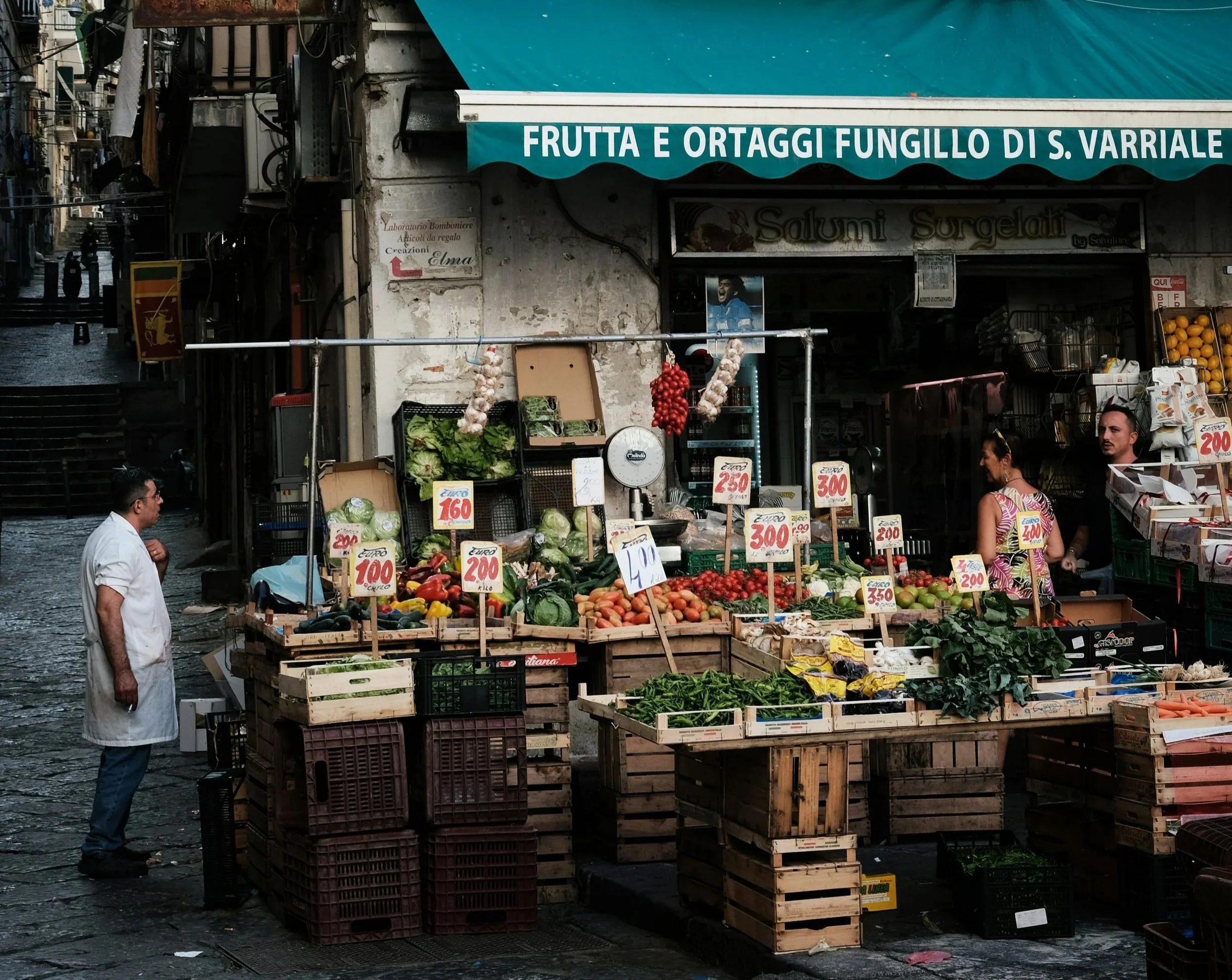 Neapolitan market vendor speaking with customers, showcasing the warmth, tradition and community of Naples