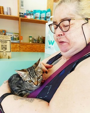 Mujer en una tienda veterinaria sosteniendo un gato en sus brazos