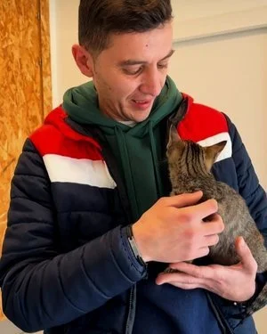 Un joven sosteniendo y acariciando a un gato.
