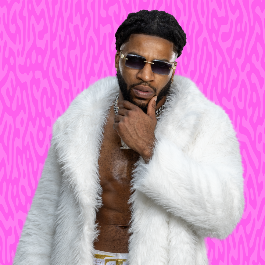 A man with sunglasses and an earring, wearing a white fur coat, posing with his hand on his chin against a bright pink, leopard-print patterned background.